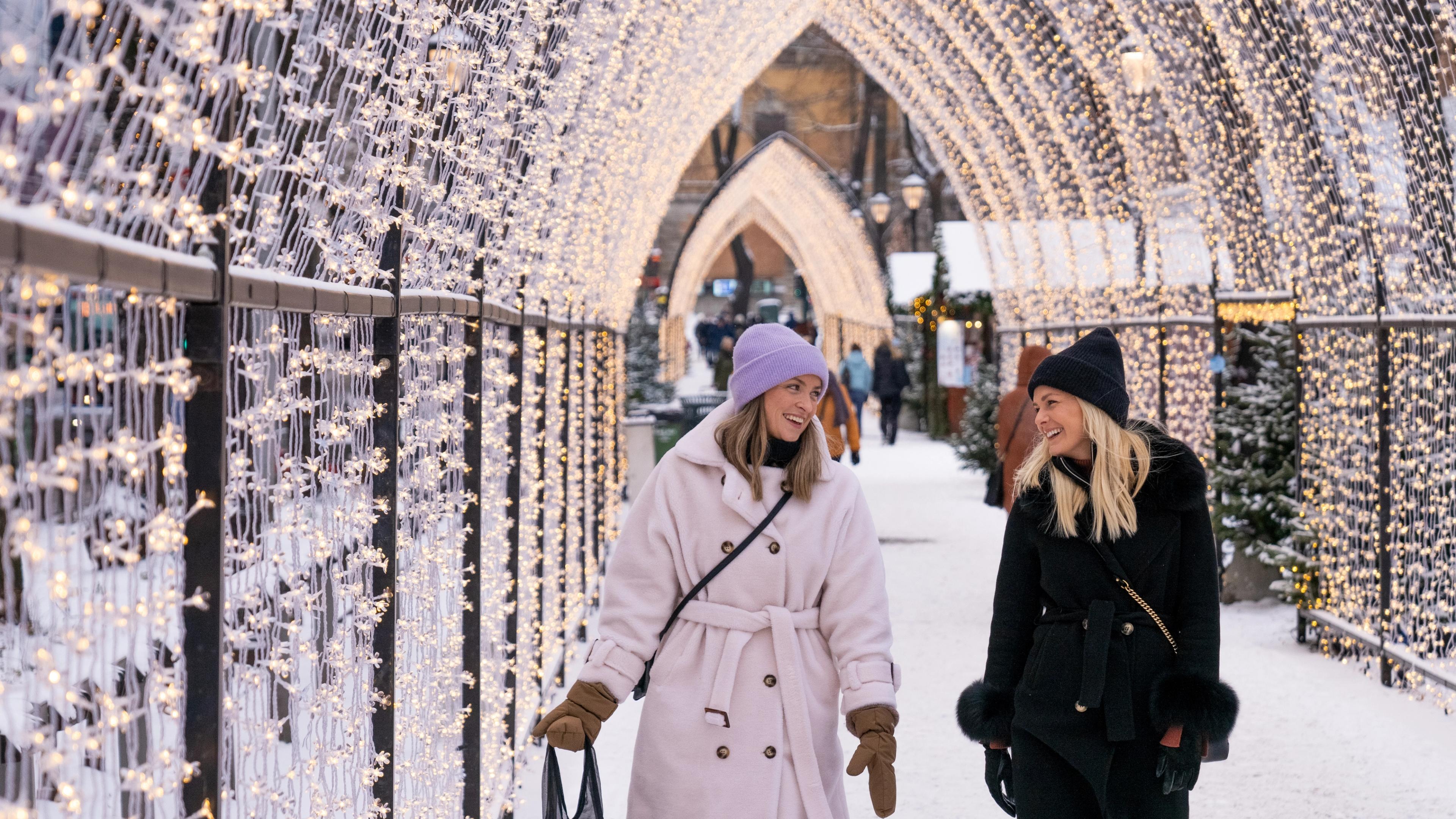 Two women walking through the lit Christmas market in Oslo, Eastern Norway