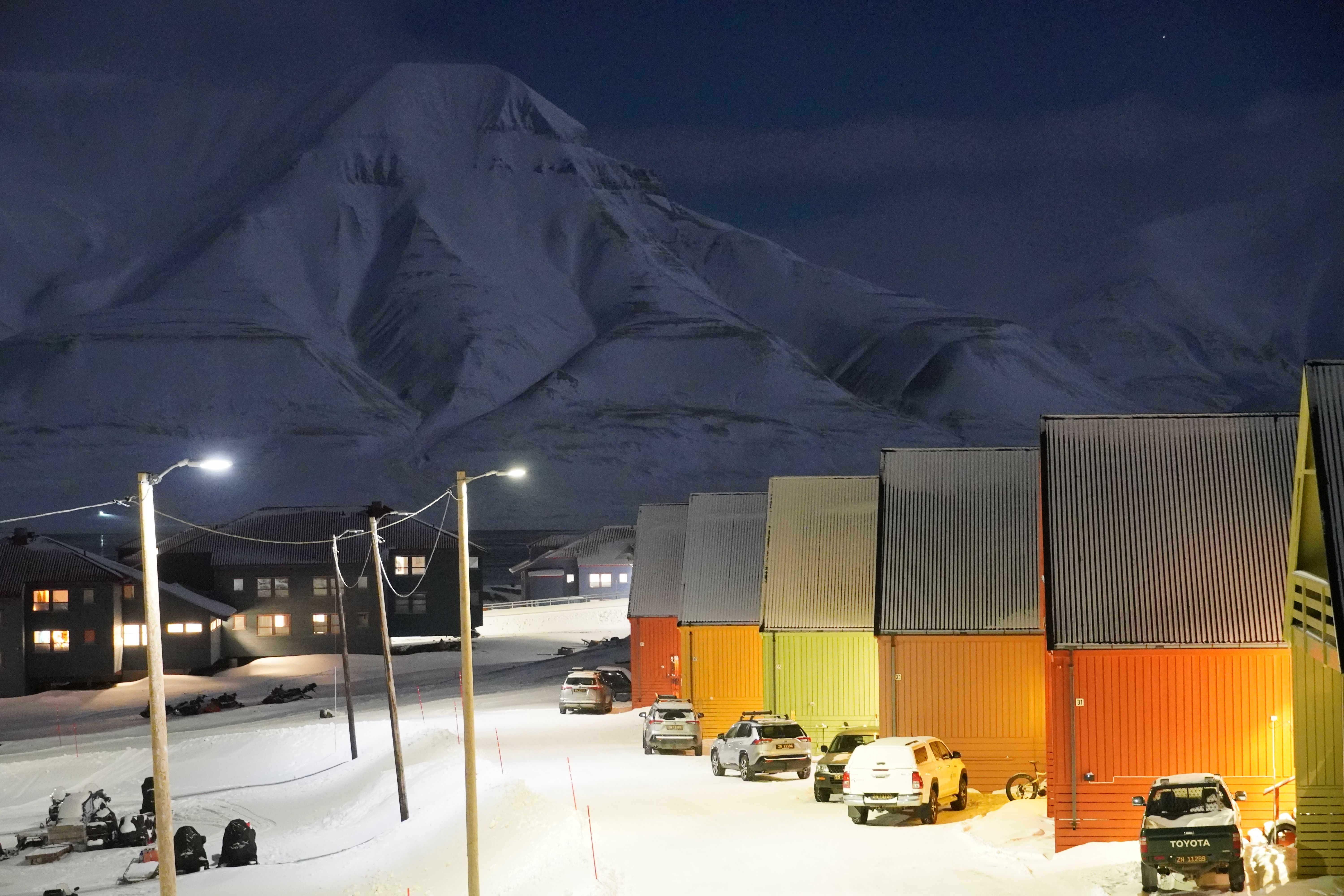 Colorful houses and snow mobiles in front of a white mountain