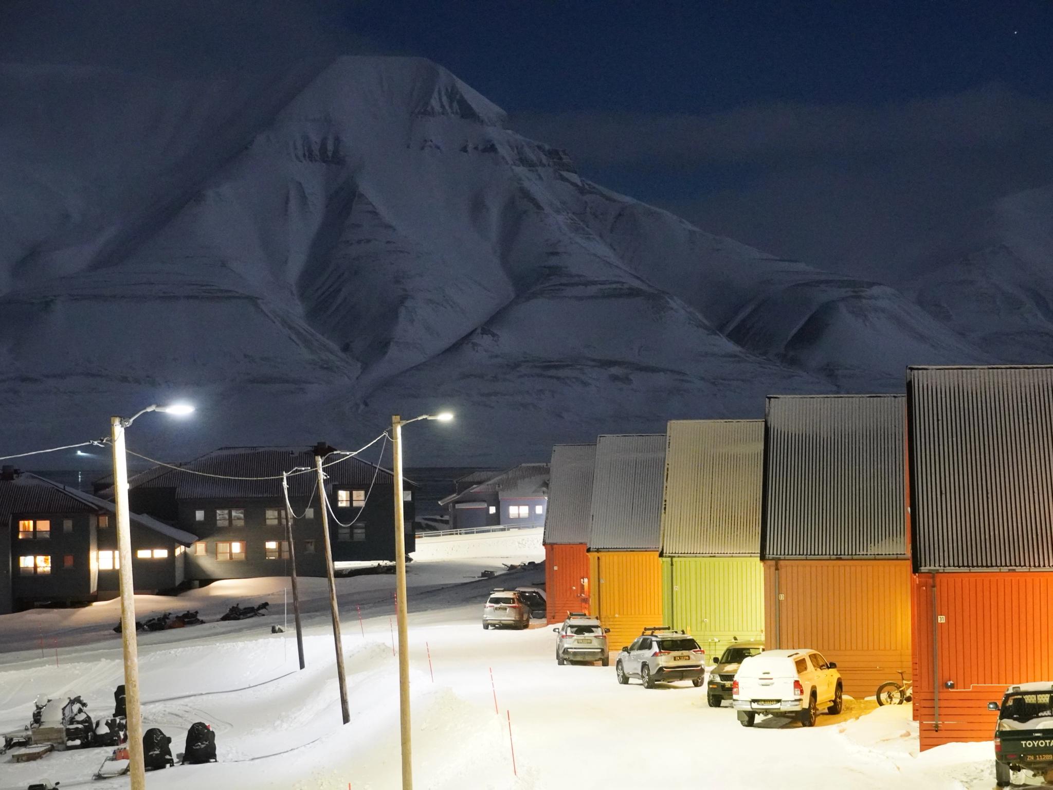 Colorful houses and snow mobiles in front of a white mountain