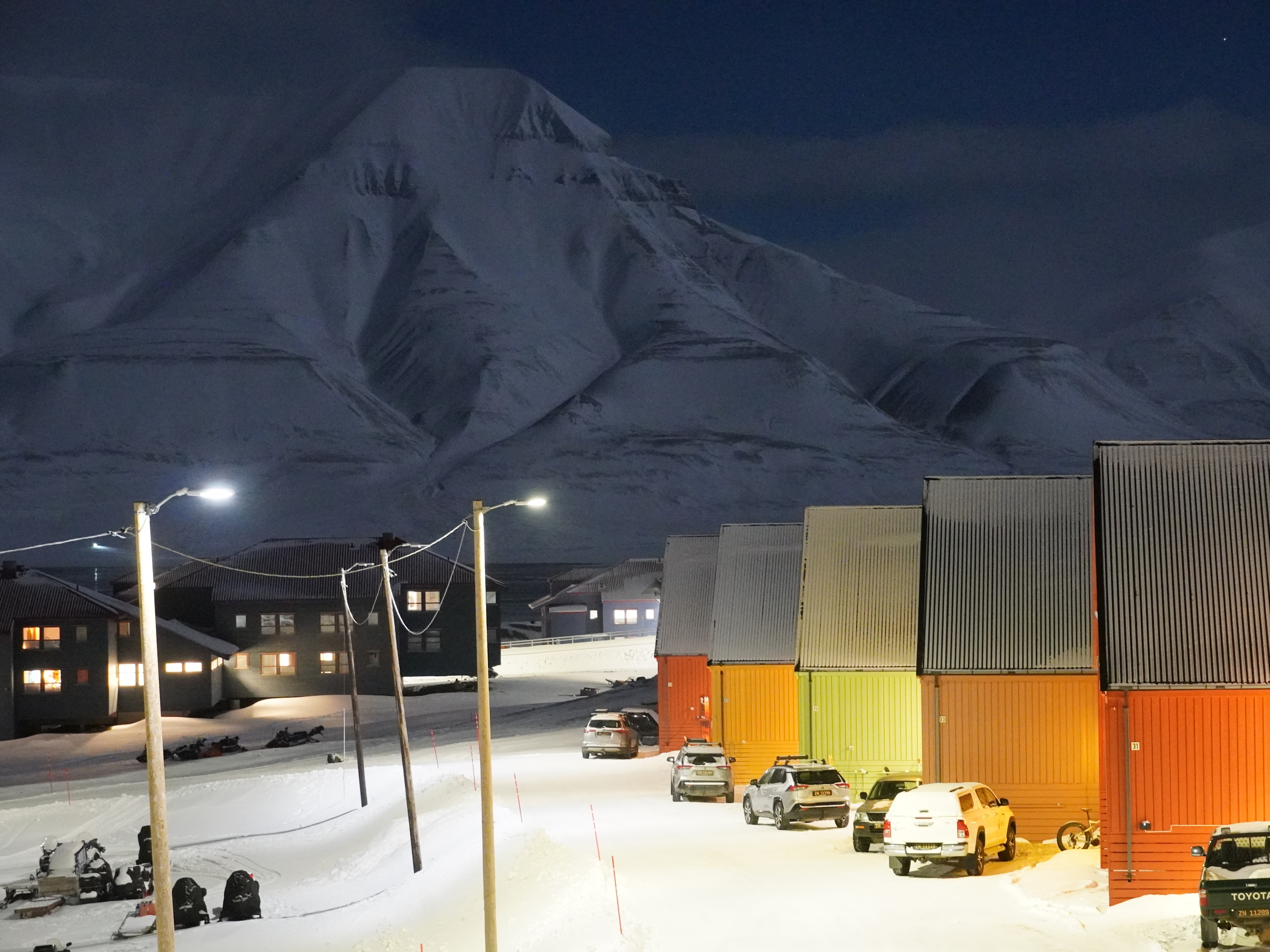 Colorful houses and snow mobiles in front of a white mountain