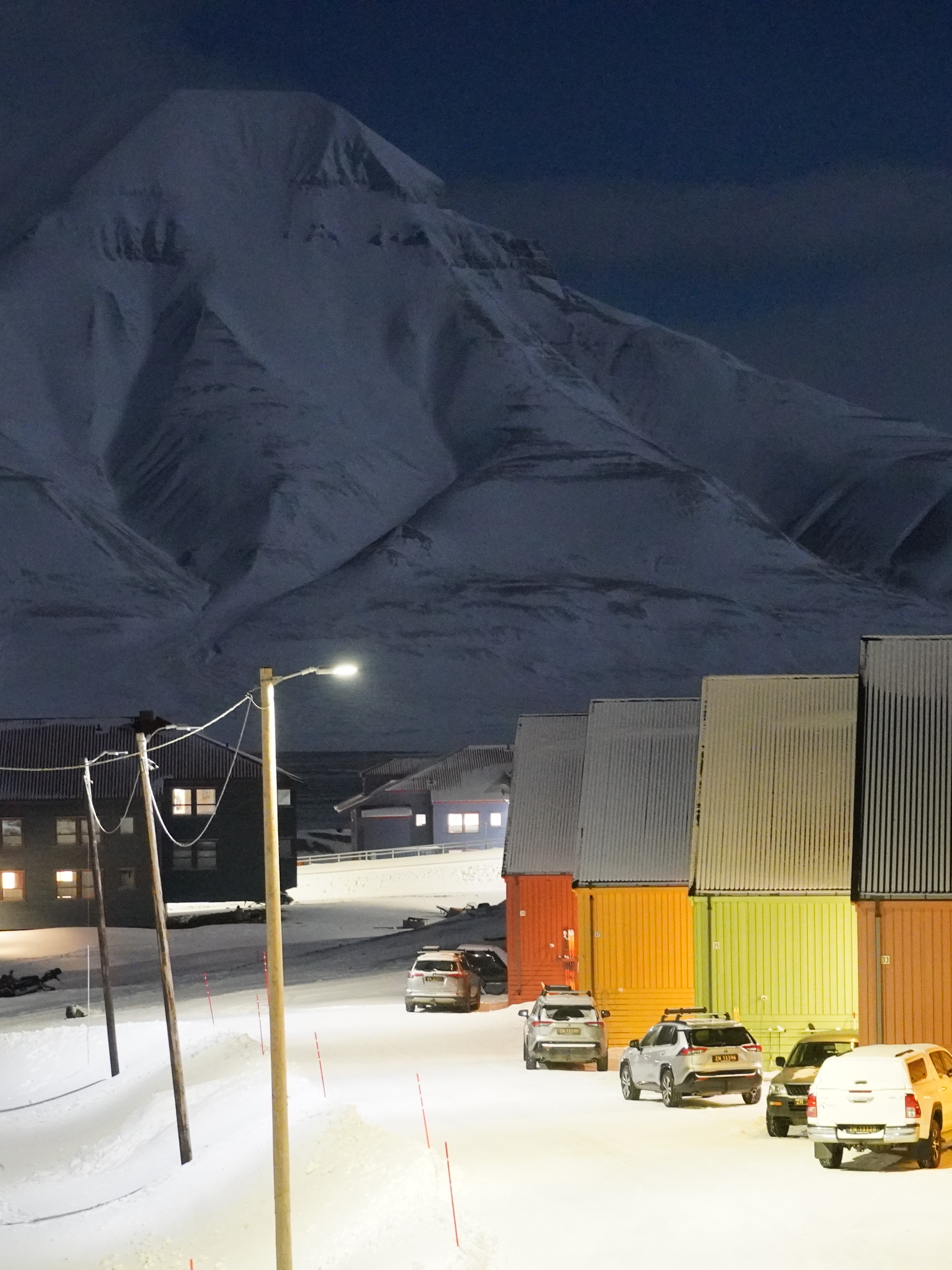 Colorful houses and snow mobiles in front of a white mountain