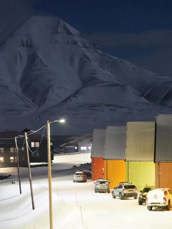 Colorful houses and snow mobiles in front of a white mountain