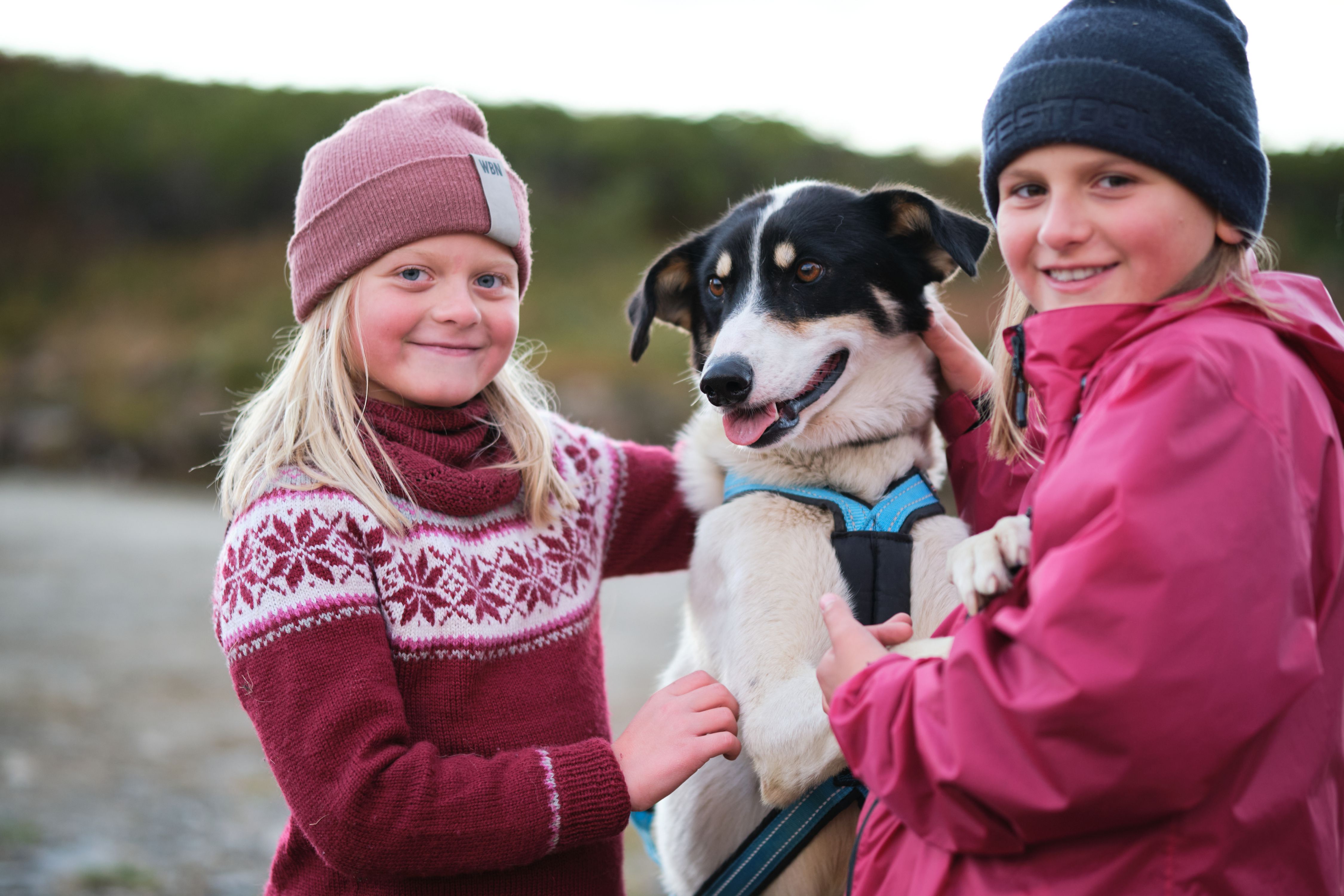 To jenter koser med en hund i Norge