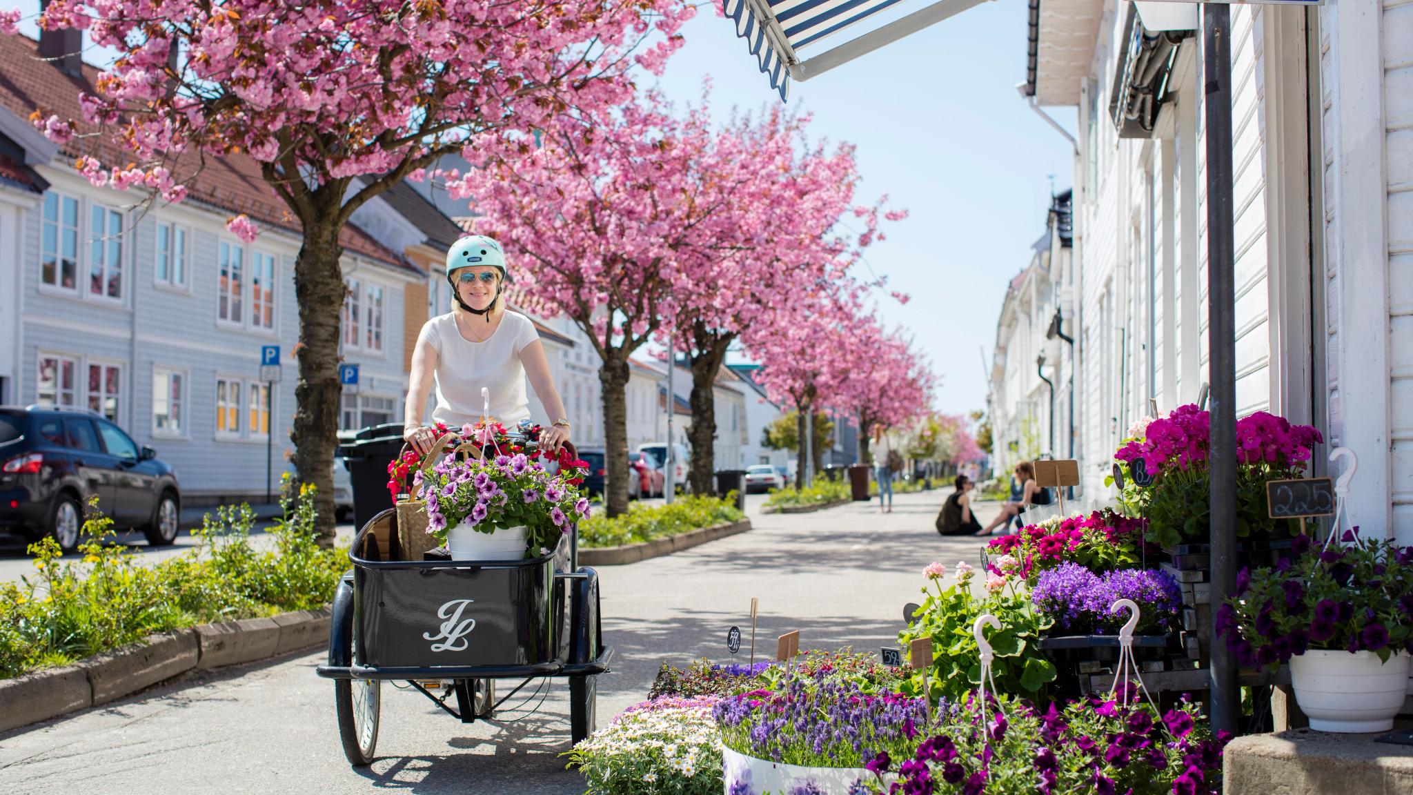 En kvinna på transportcykel full med blommor i Posebyen, Kristiansand i södra Norge