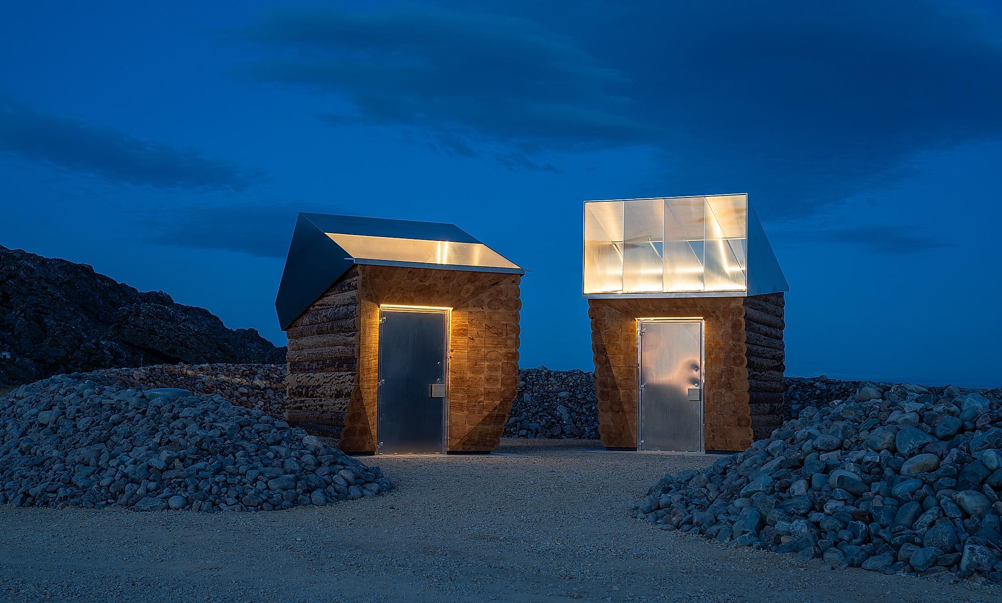 Two wooden buildings with glowing light against the night sky