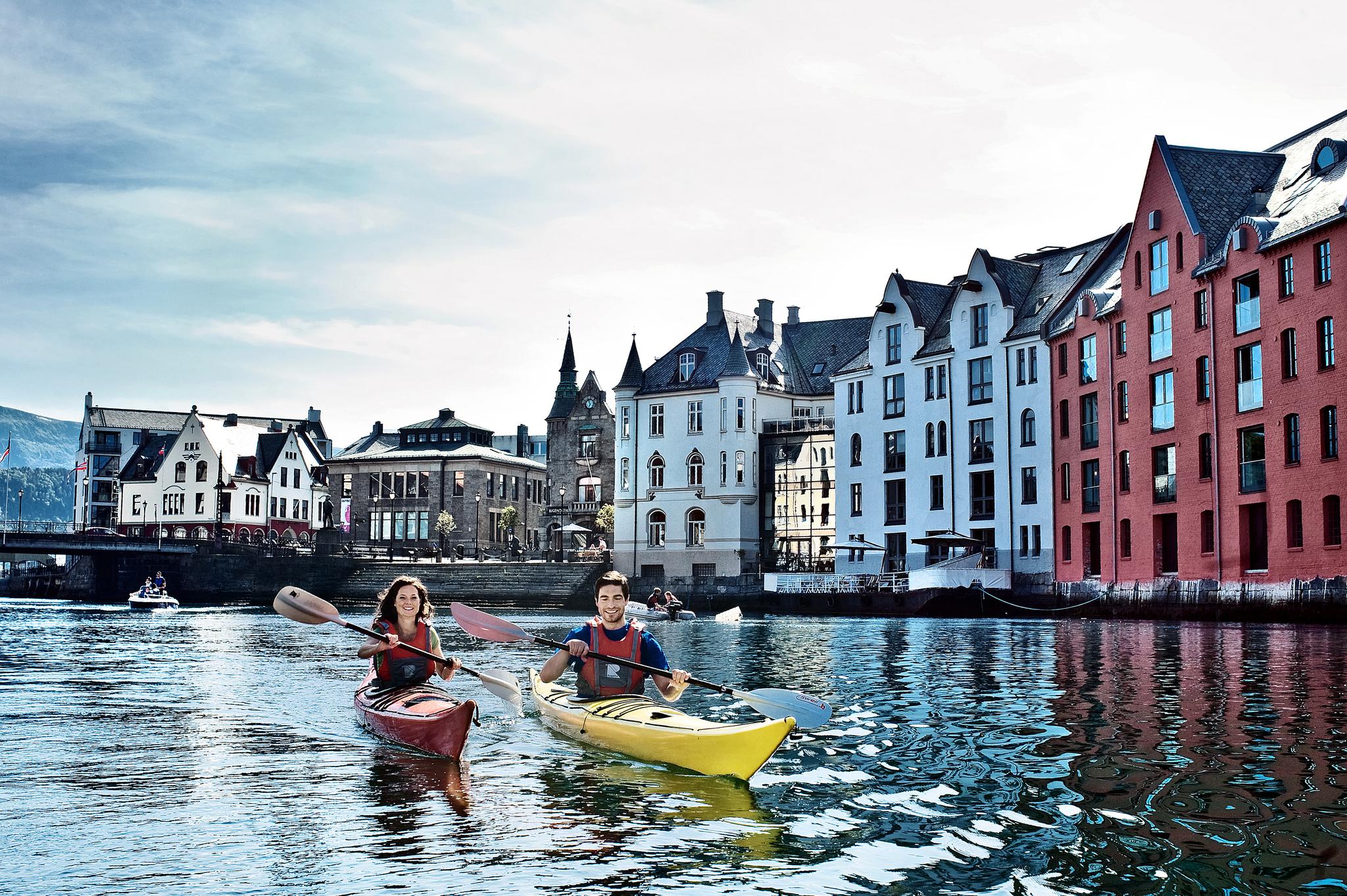 Two people kayaking through the city centre of Ålesund, Fjord Norway