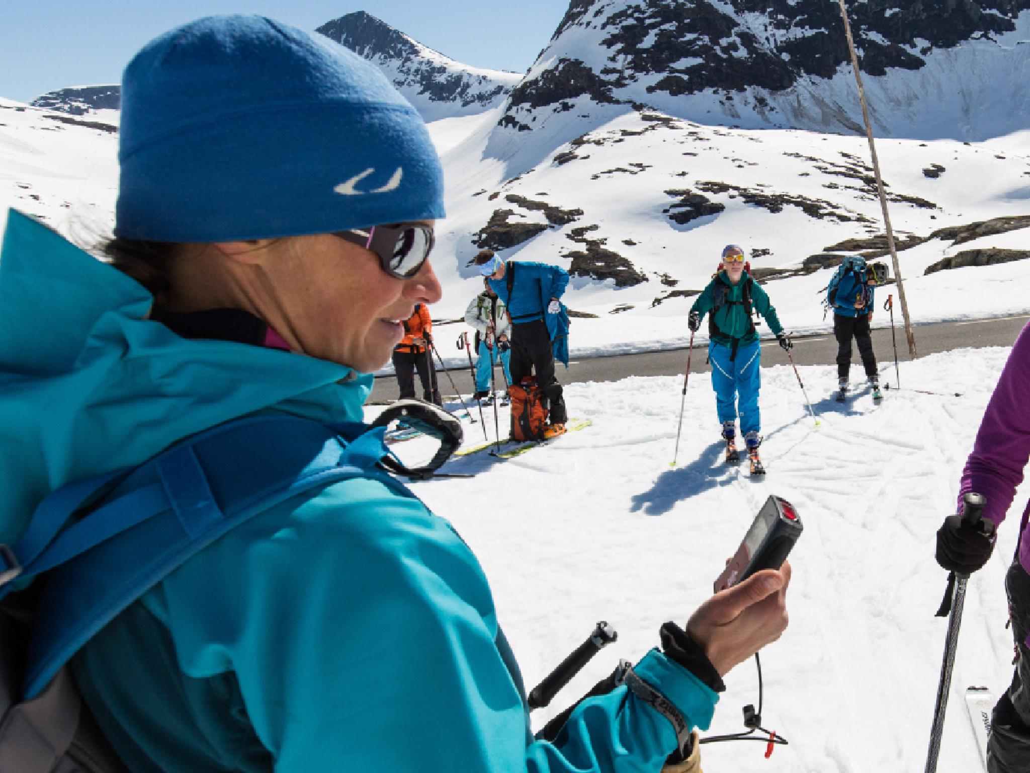 A group of seven skiers on the snow next to a small road, Norway