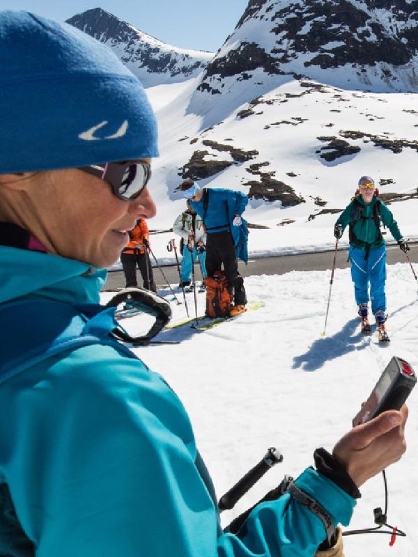 A group of seven skiers on the snow next to a small road, Norway