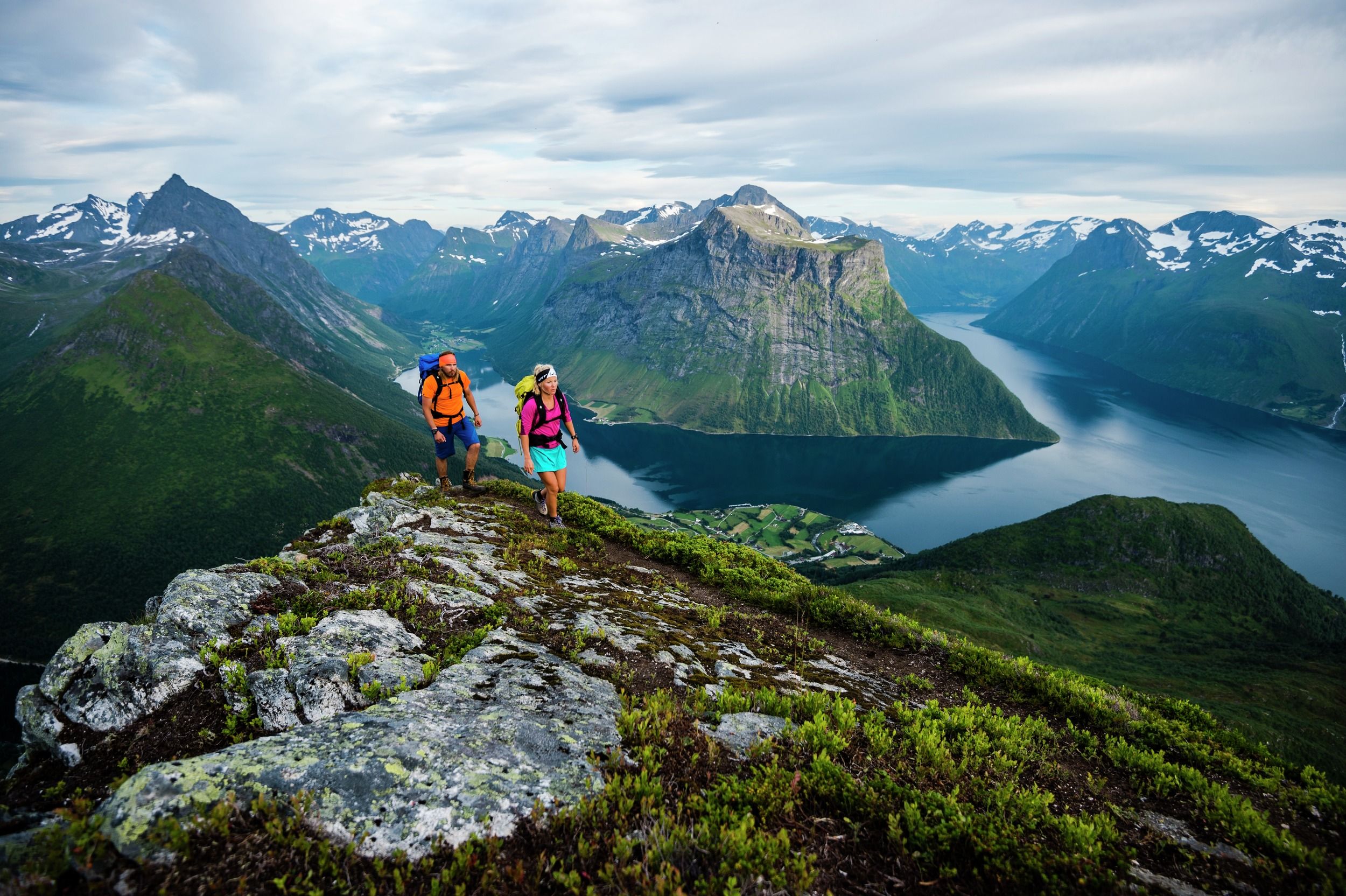 Two people are hiking the mountains of Hjørundfjorden in Fjord Norway