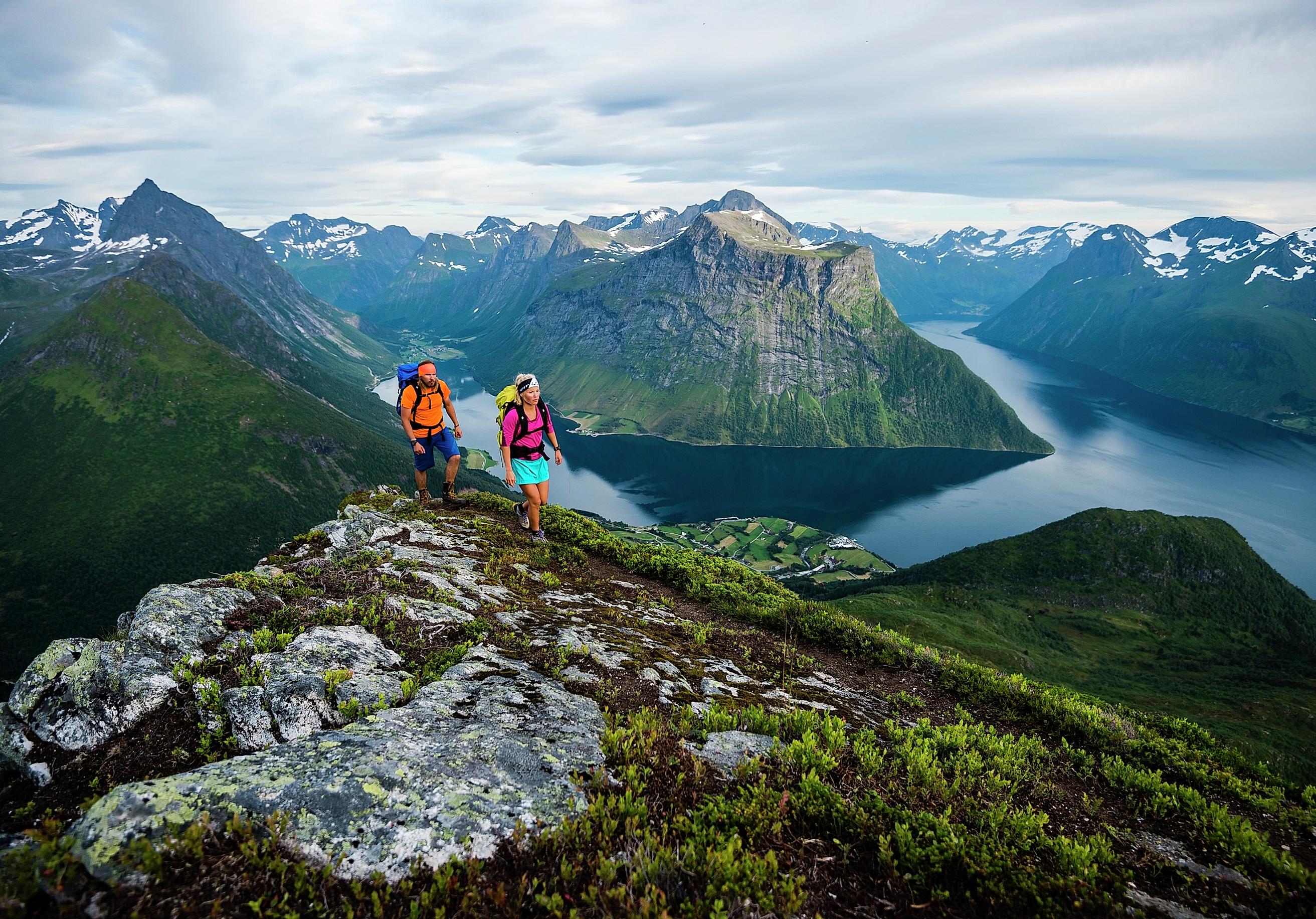 Two people are hiking the mountains of Hjørundfjorden in Fjord Norway