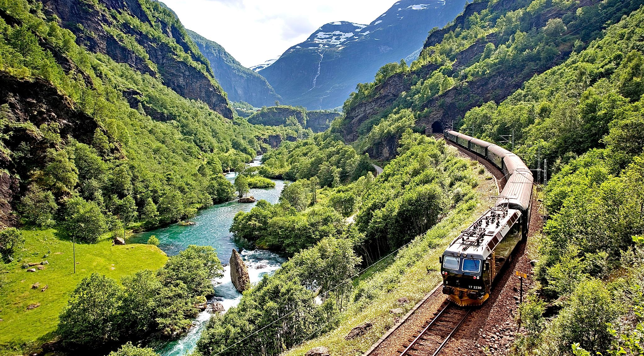 The Flåm railway going through the landscape of green hills and spectacular mountains in Fjord Norway