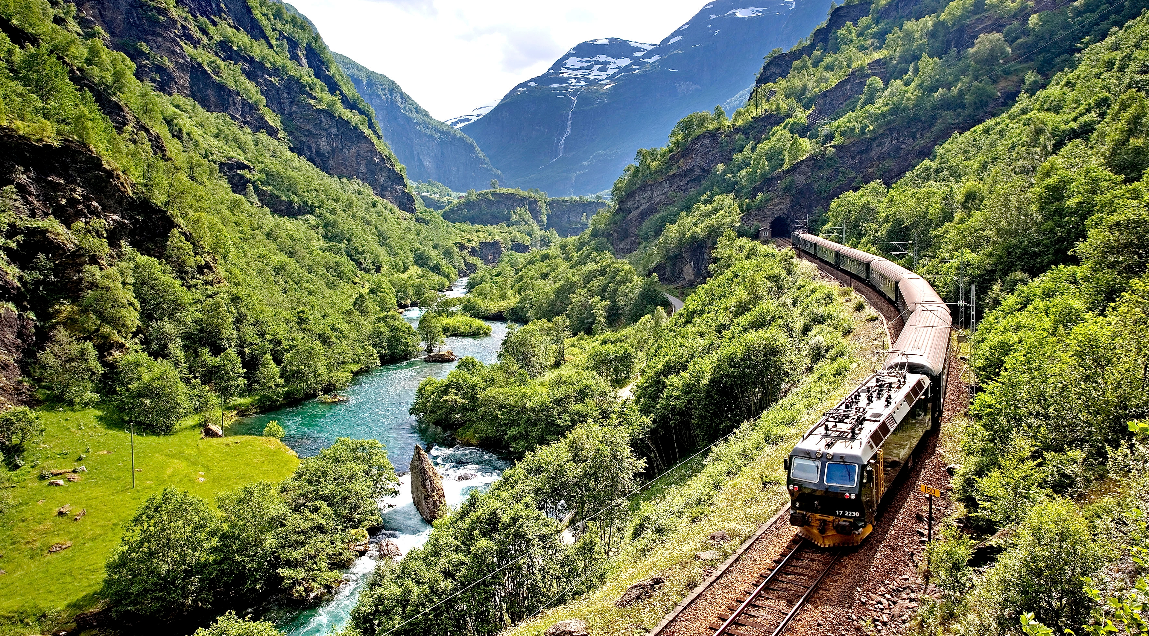 The Flåm railway going through the landscape of green hills and spectacular mountains in Fjord Norway