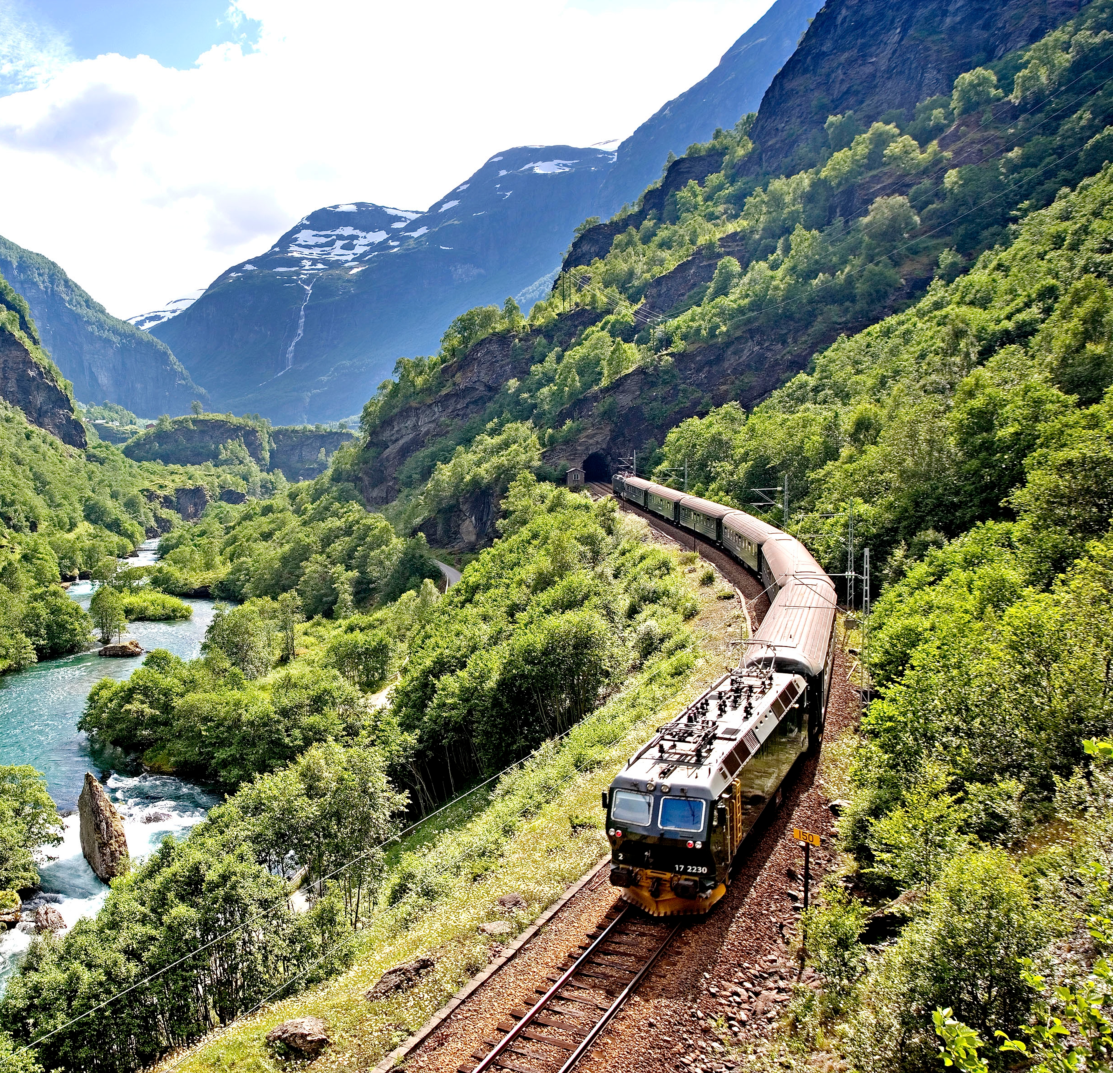 The Flåm railway going through the landscape of green hills and spectacular mountains in Fjord Norway