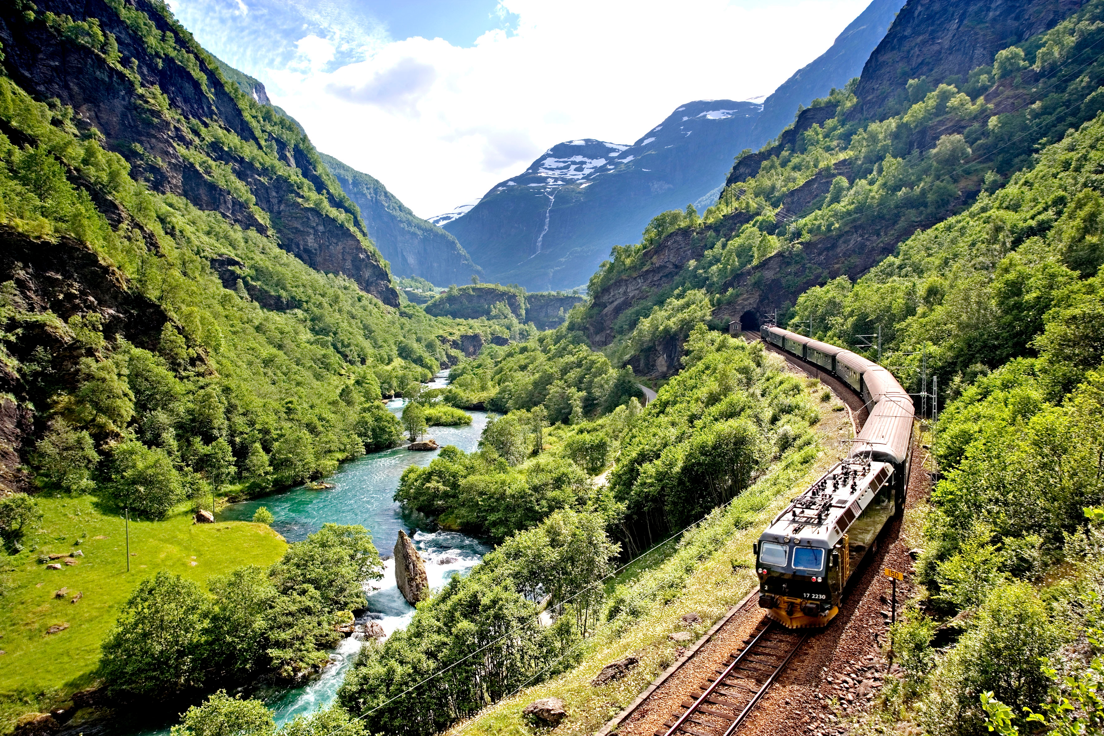 The Flåm railway going through the landscape of green hills and spectacular mountains in Fjord Norway