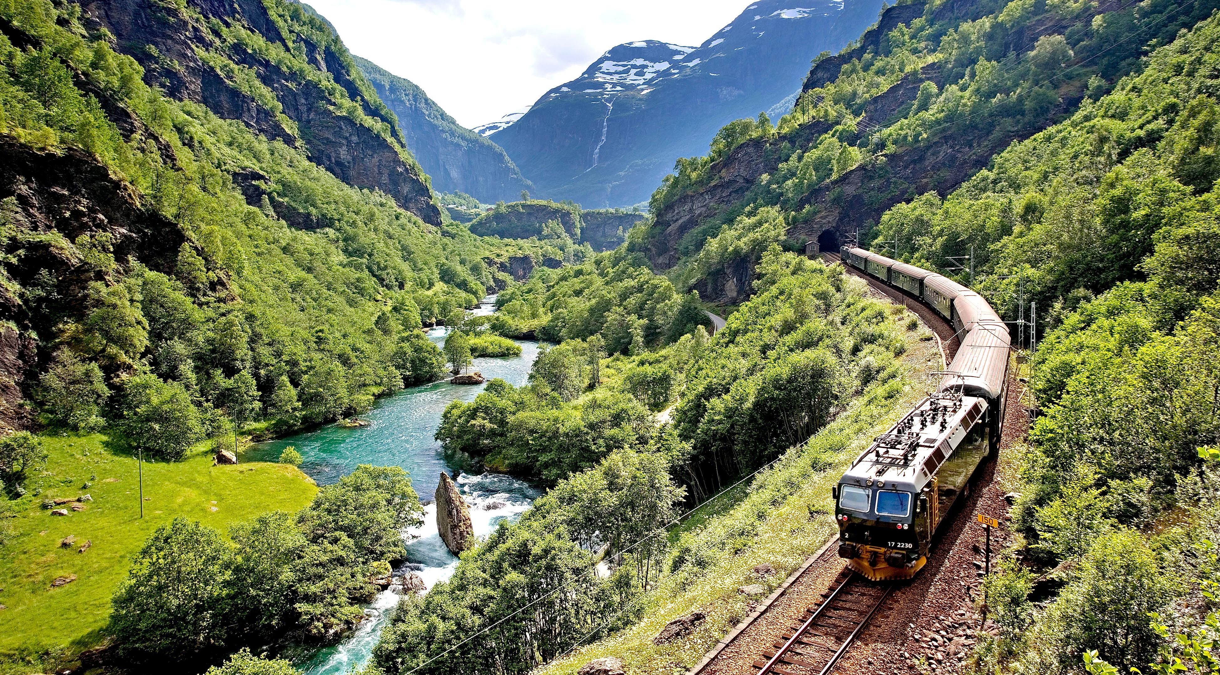 The Flåm railway going through the landscape of green hills and spectacular mountains in Fjord Norway