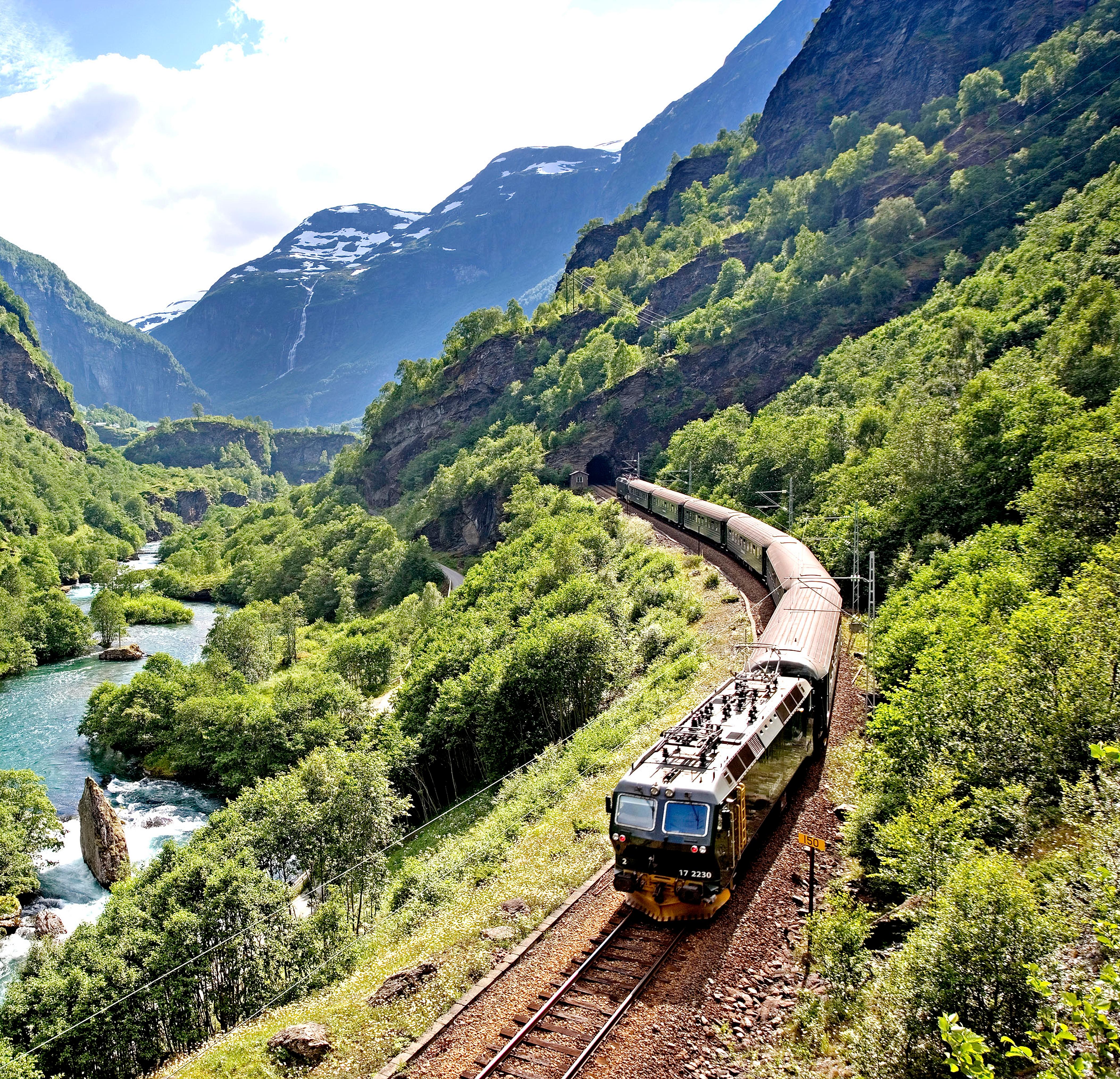 The Flåm railway going through the landscape of green hills and spectacular mountains in Fjord Norway