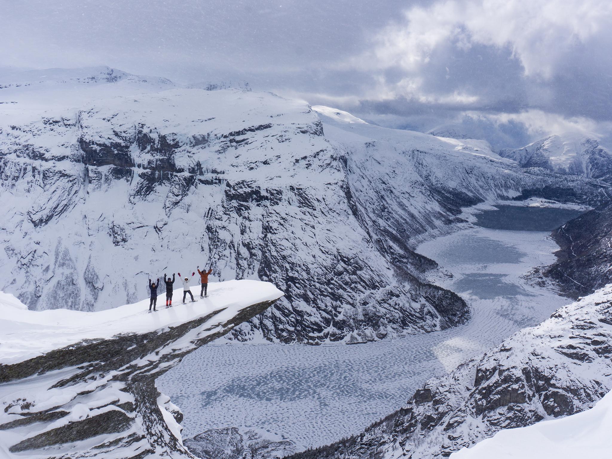 Quatre randonneurs au sommet du Trolltunga, en Norvège des Fjords, en hiver, raquettes aux pieds