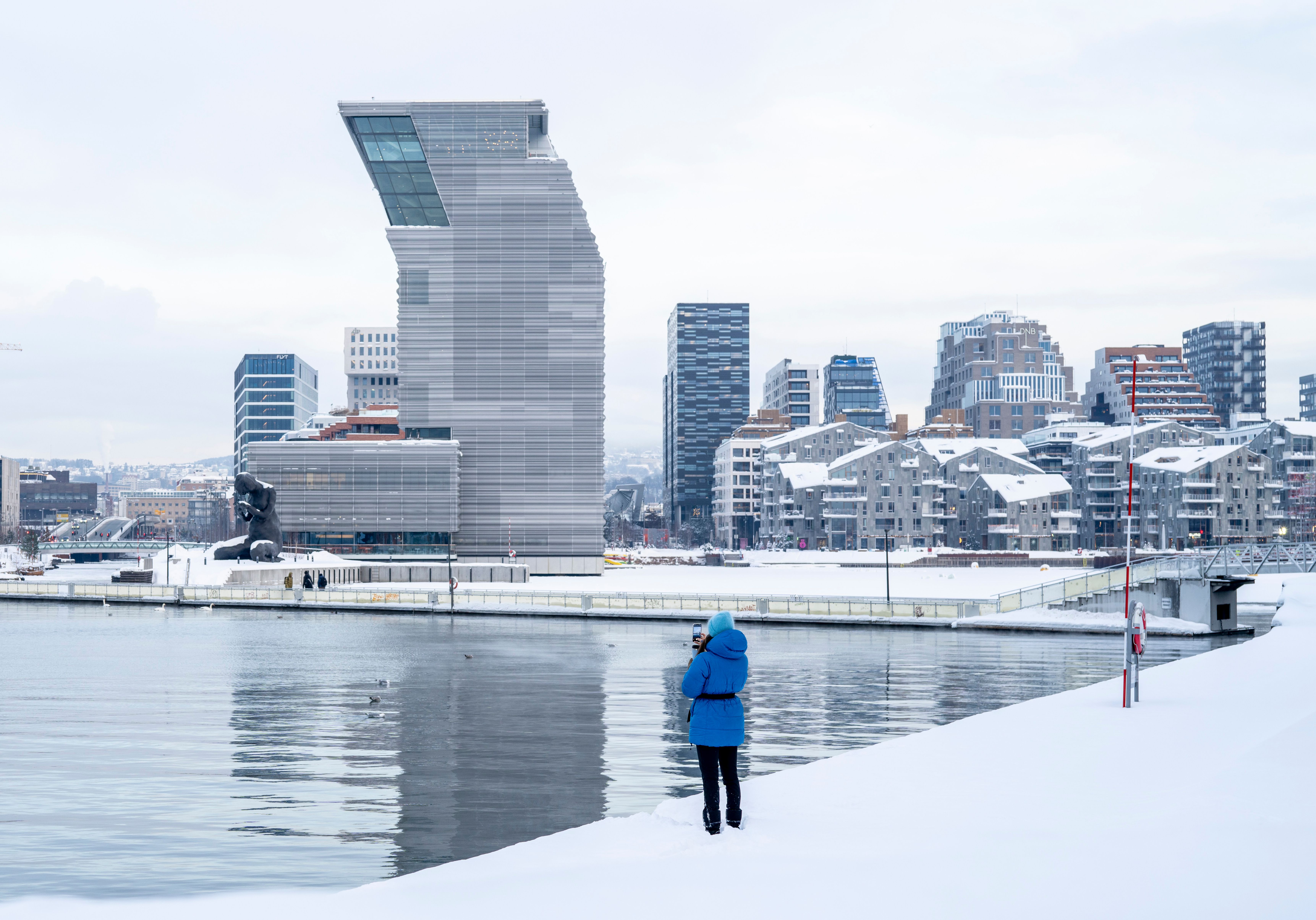 Woman in front of buildings like the MUNCH museum in Bjørvika in Oslo