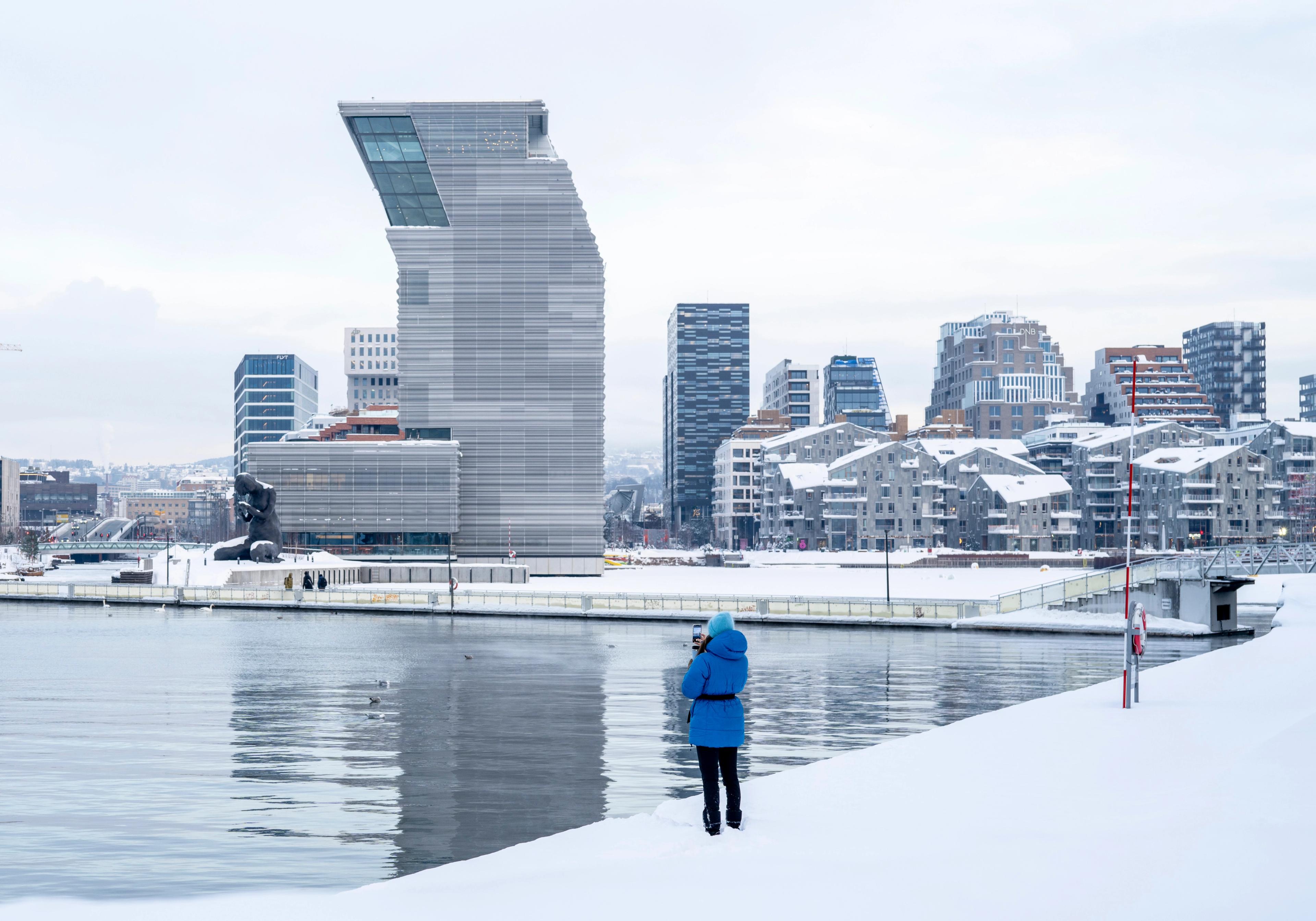 Woman in front of buildings like the MUNCH museum in Bjørvika in Oslo