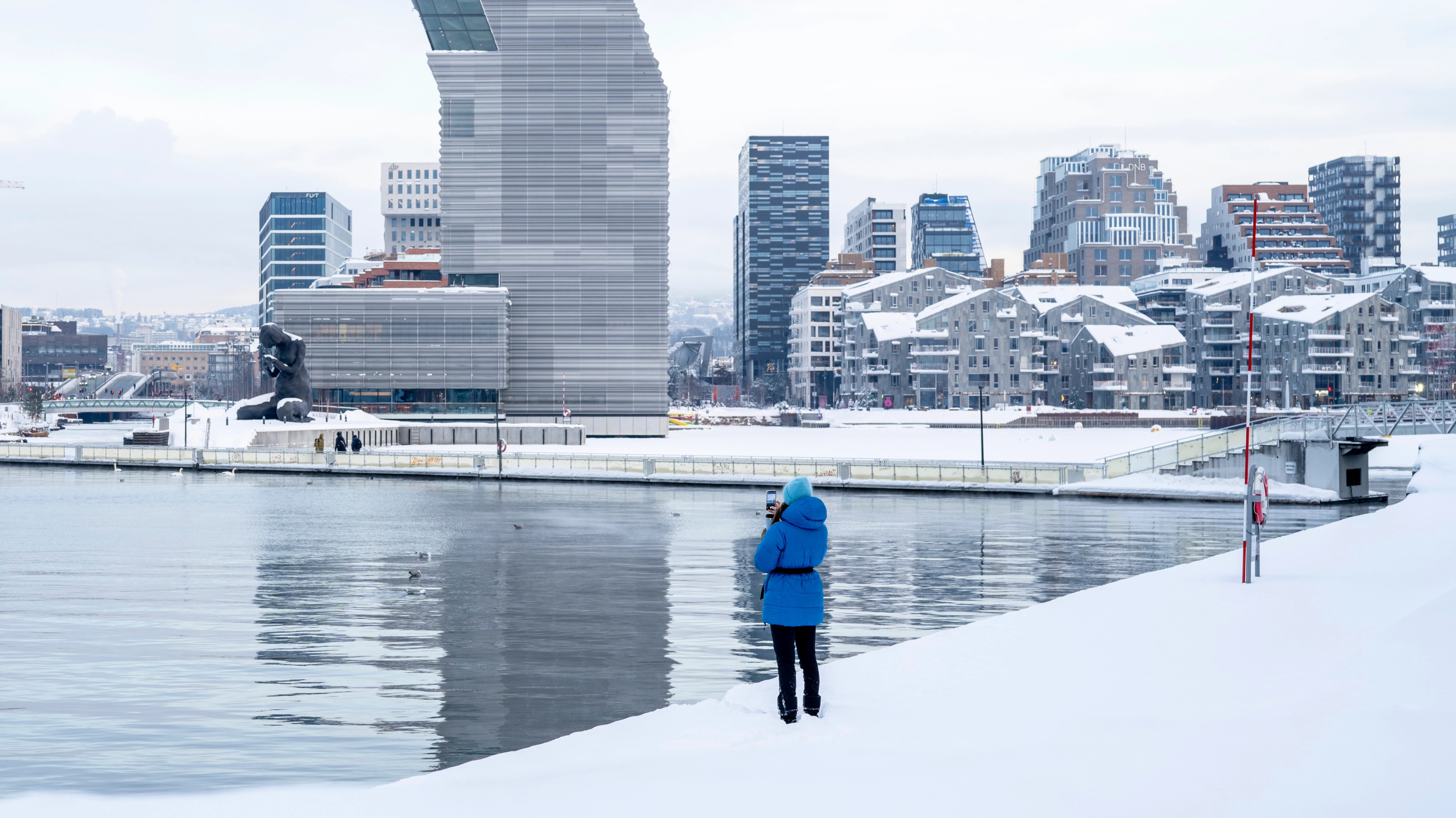 Woman in front of buildings like the MUNCH museum in Bjørvika in Oslo