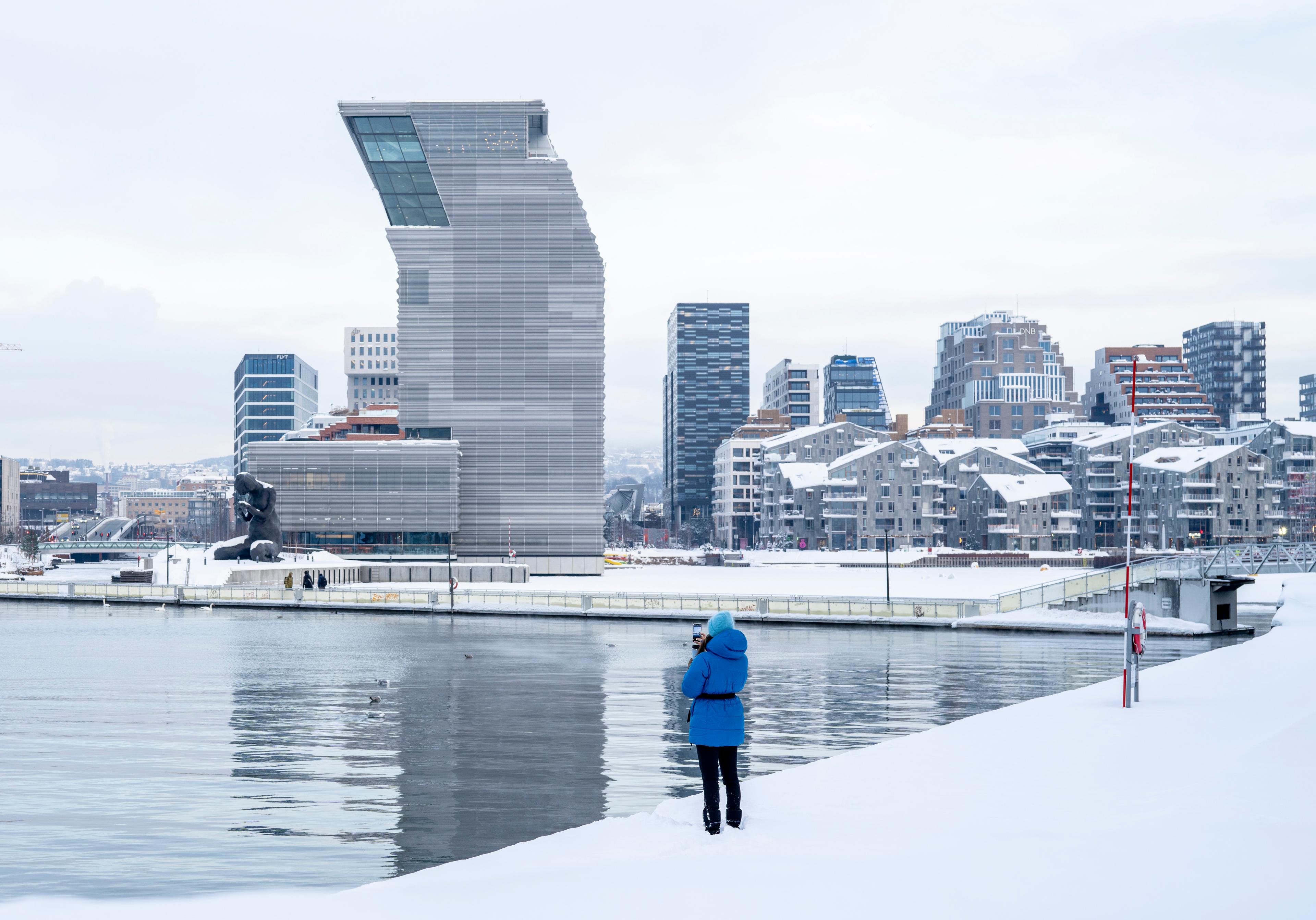 Woman in front of buildings like the MUNCH museum in Bjørvika in Oslo