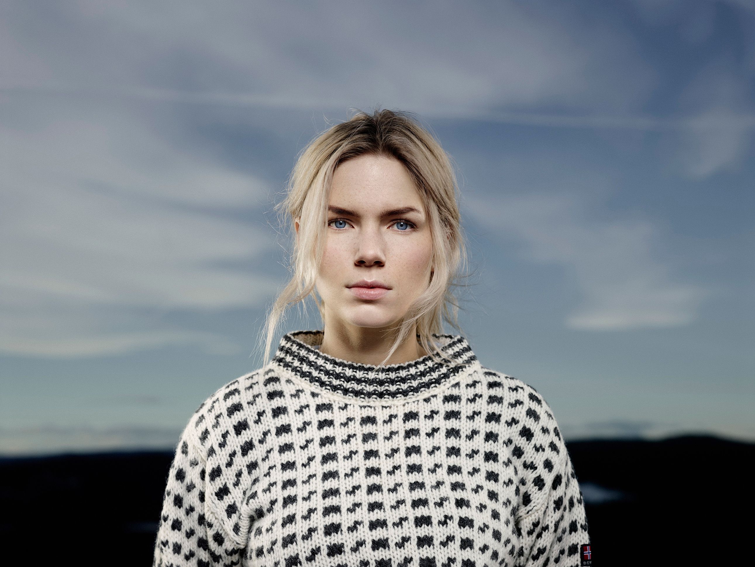 Close-up shot of a girl with a white woollen sweater with black motives