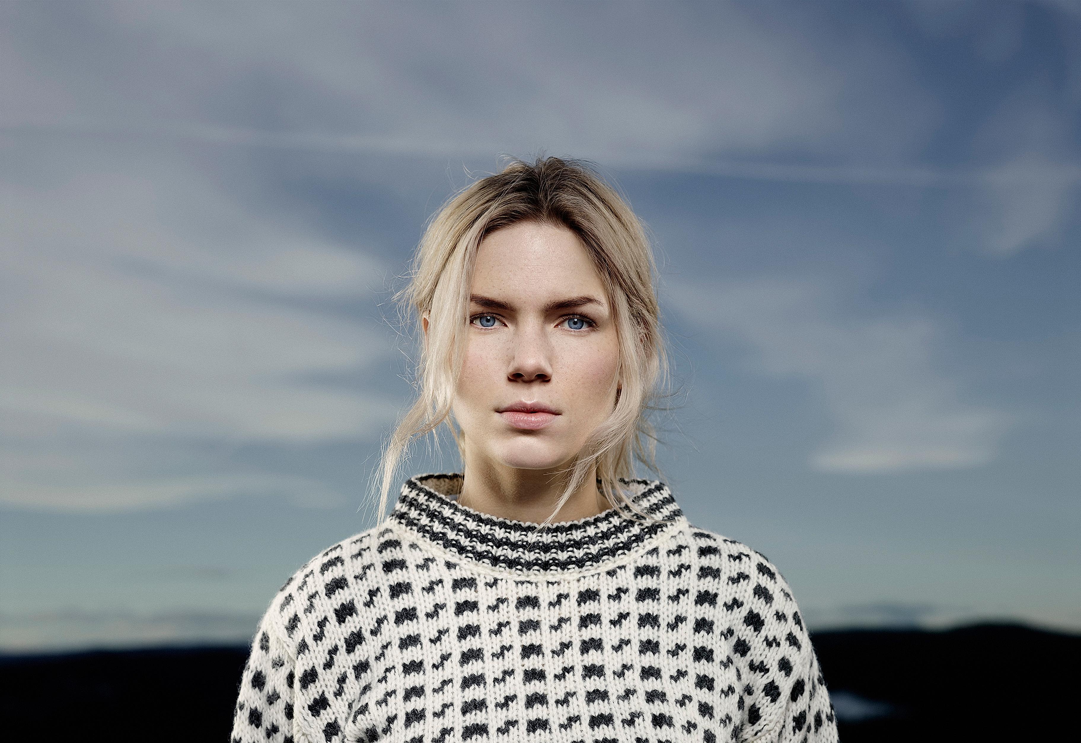 Close-up shot of a girl with a white woollen sweater with black motives