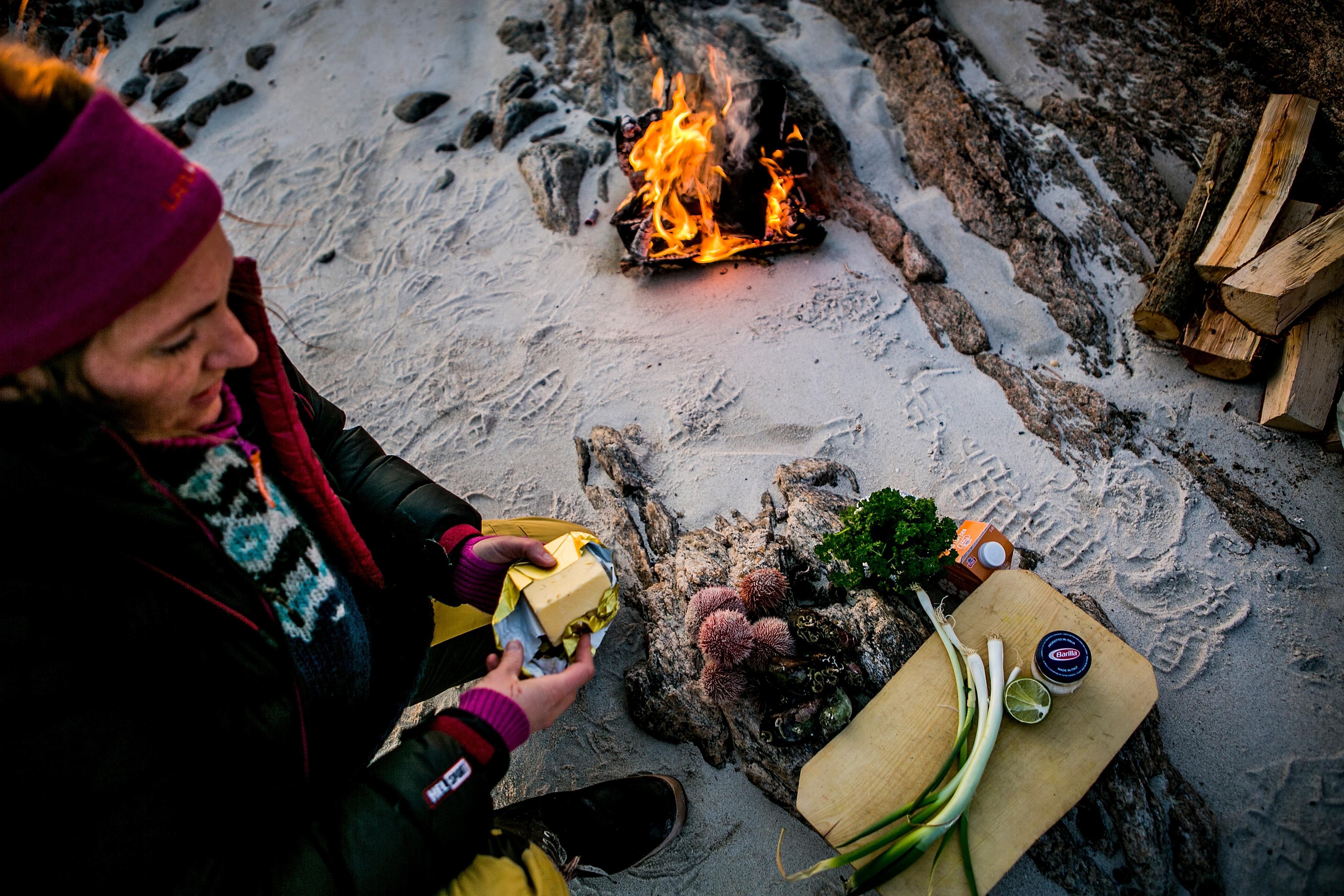 En dame lager mat på stranden i Steigen i Nordland, Nord-Norge
