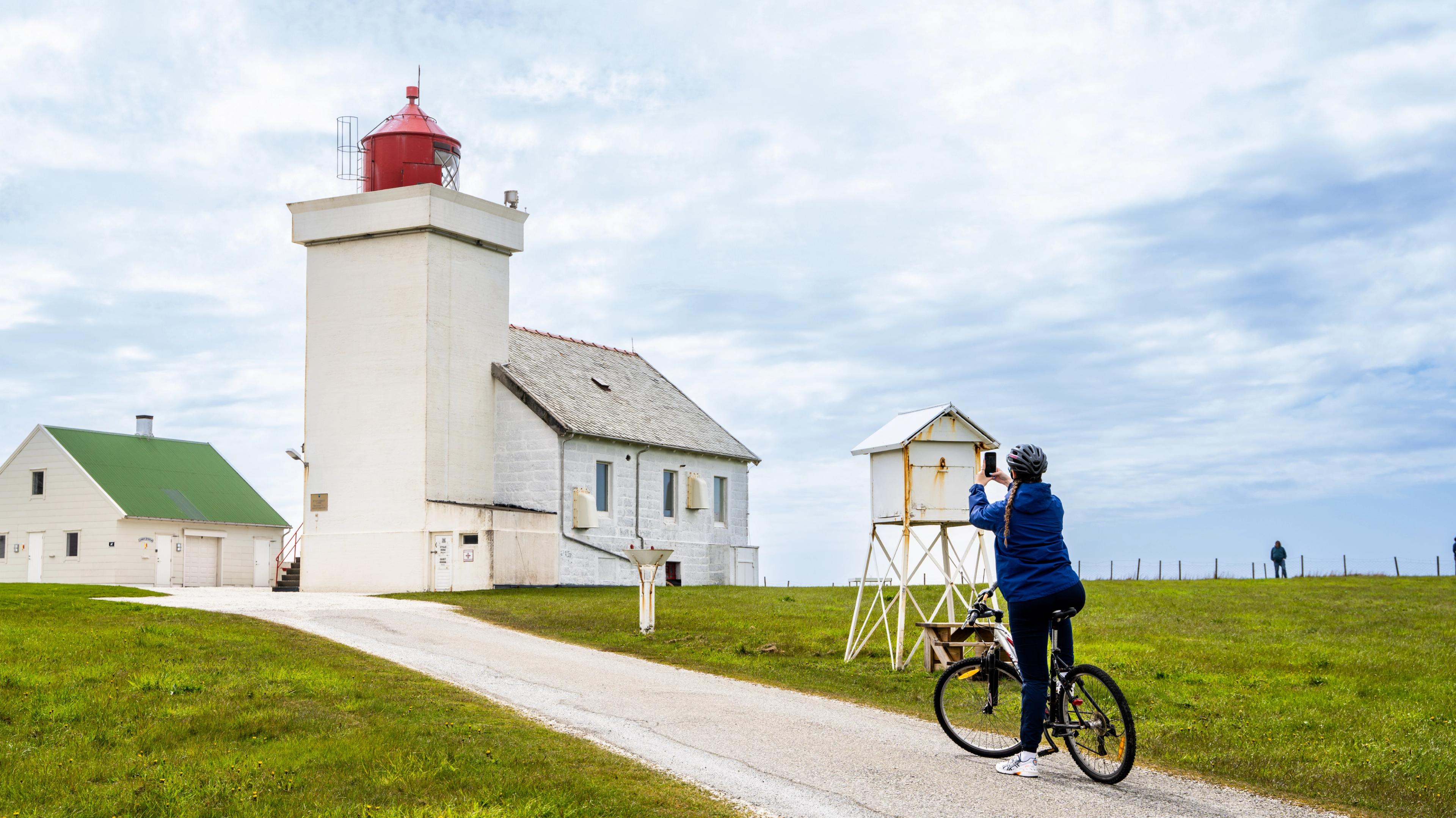 A woman taking a picture of the Obrestad lighthouse at the Jæren coast, Fjord Norway.