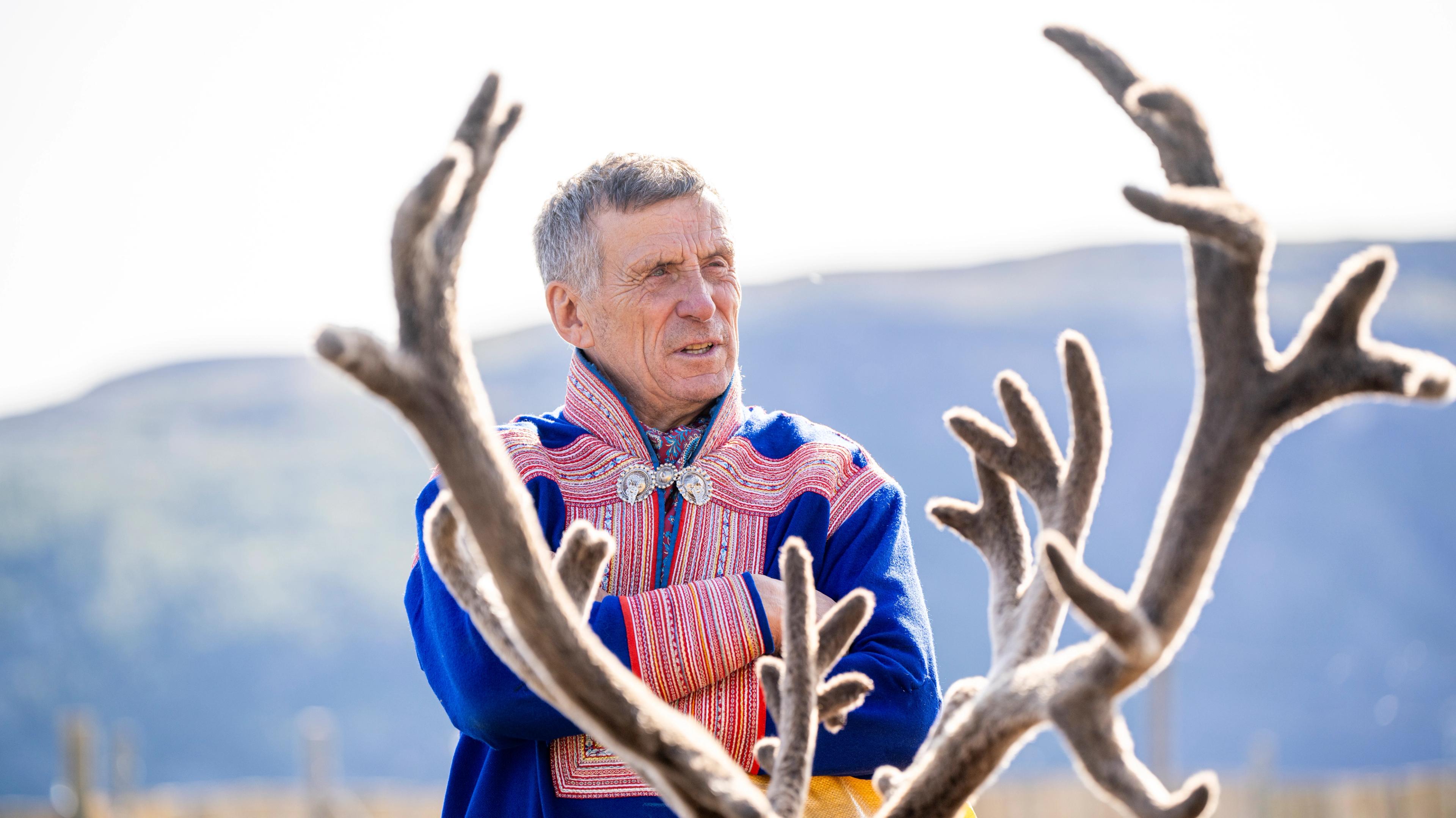 Portrait of the reindeer herder Nils Henrik Sara with reindeer antlers in the foreground