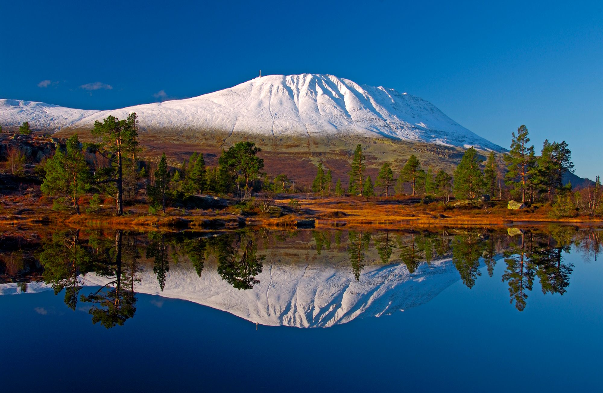 Det snedækkede fjeld Gaustatoppen spejler sig i en sø i Telemark, Norge