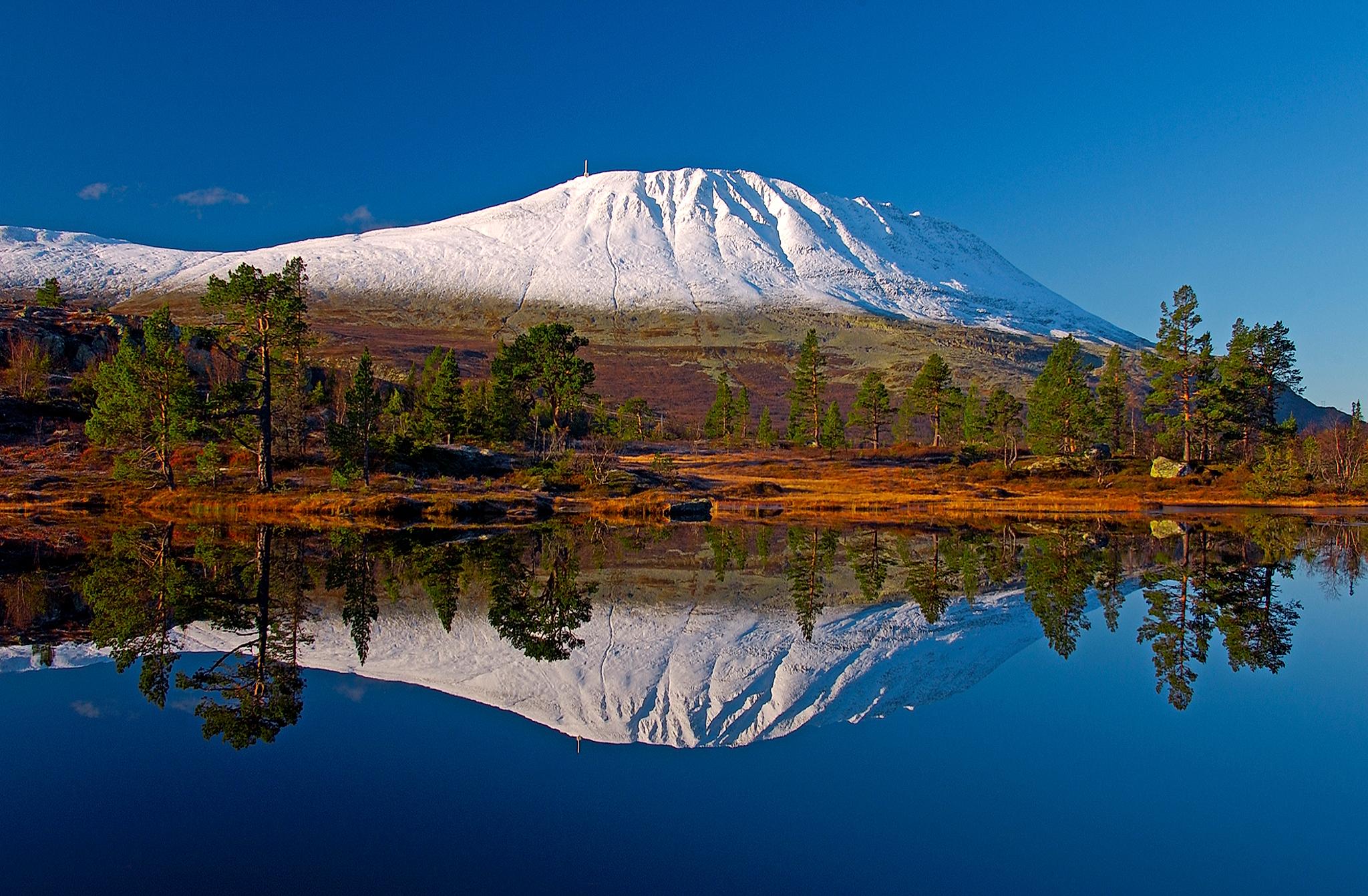 A snow-covered Gaustatoppen reflecting in a lake, Telemark, Norway
