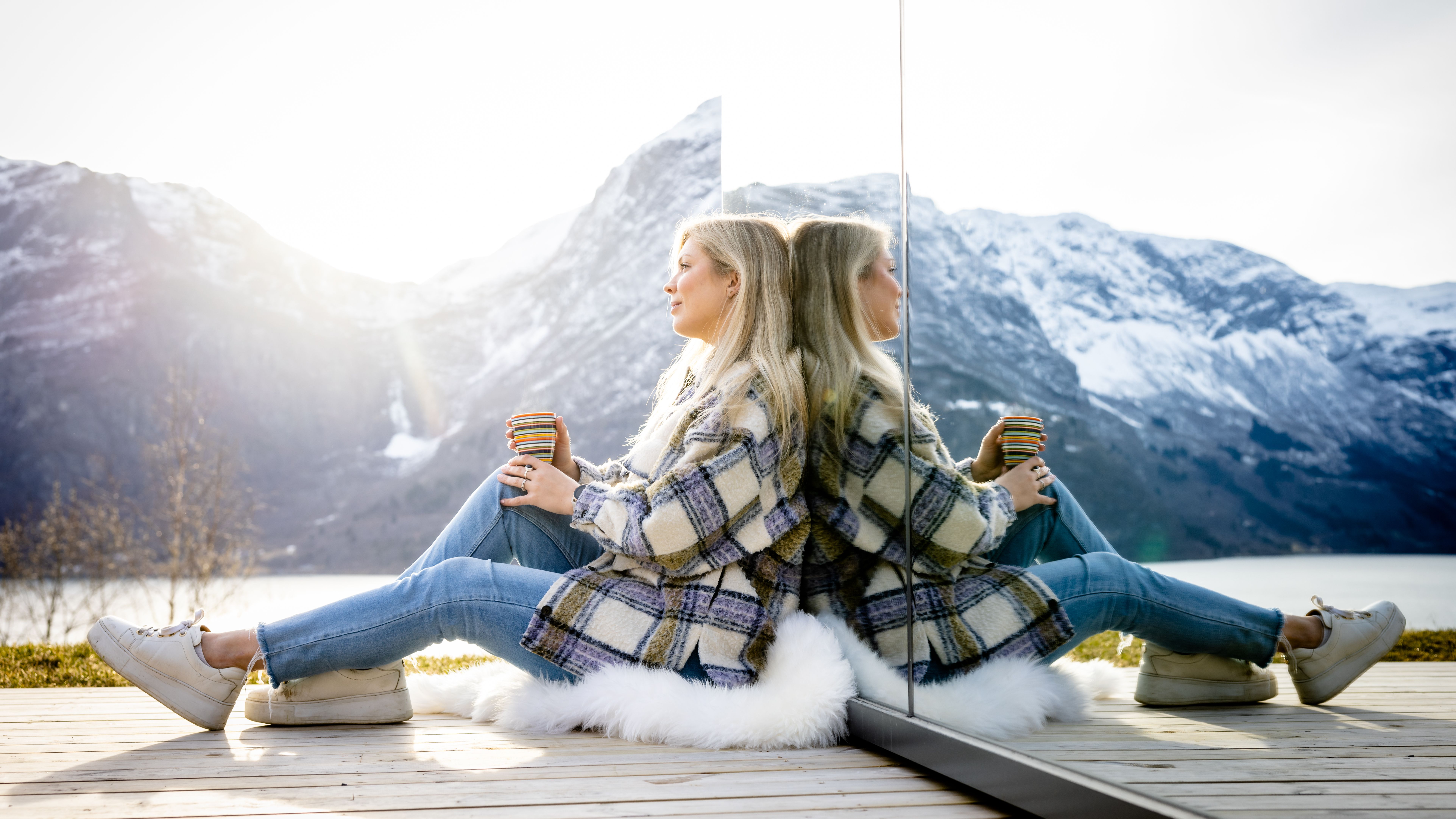 A woman sitting in front of the The Fjord Mirror in Nes Gard in Luster