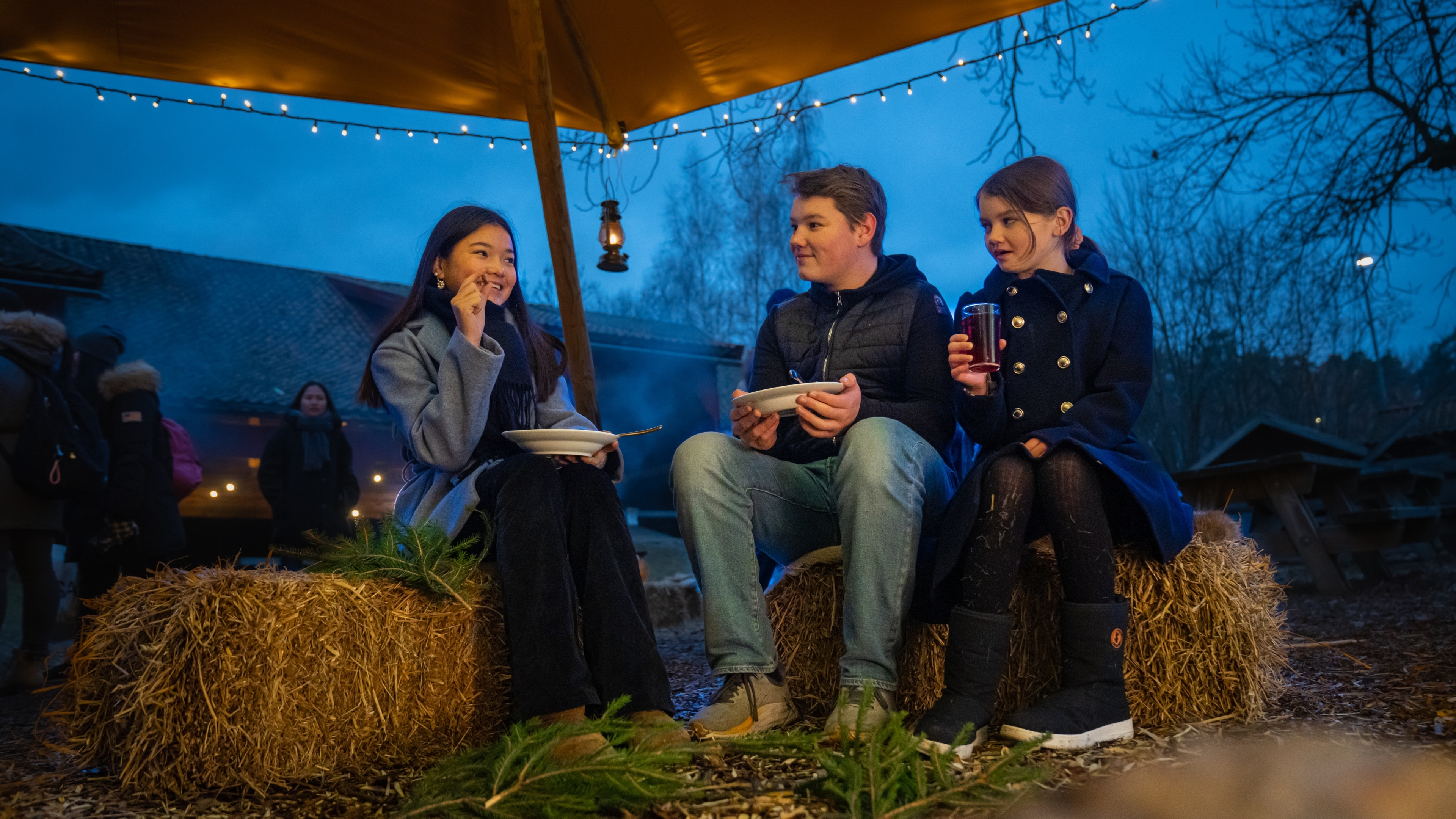 Three kids are eating porridge at the Christmas market in Norsk Folkemuseum in Bygdøy, Eastern Norway