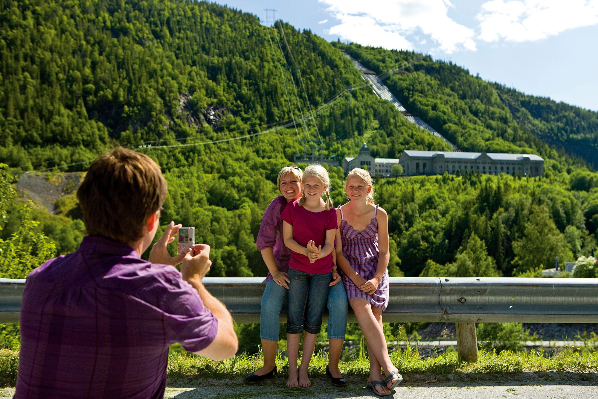 En person fotograferer tre barn foran Norsk industriarbeidermuseum i Vemork i Telemark