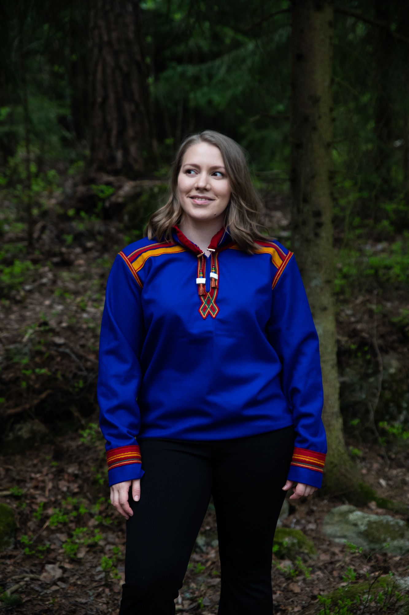 Eirin Roseneng in the woods in a blue Sami inspired hoodie