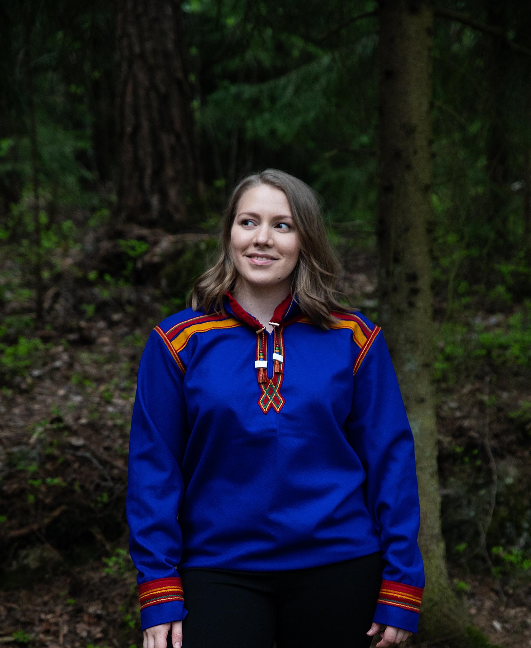 Eirin Roseneng in the woods in a blue Sami inspired hoodie