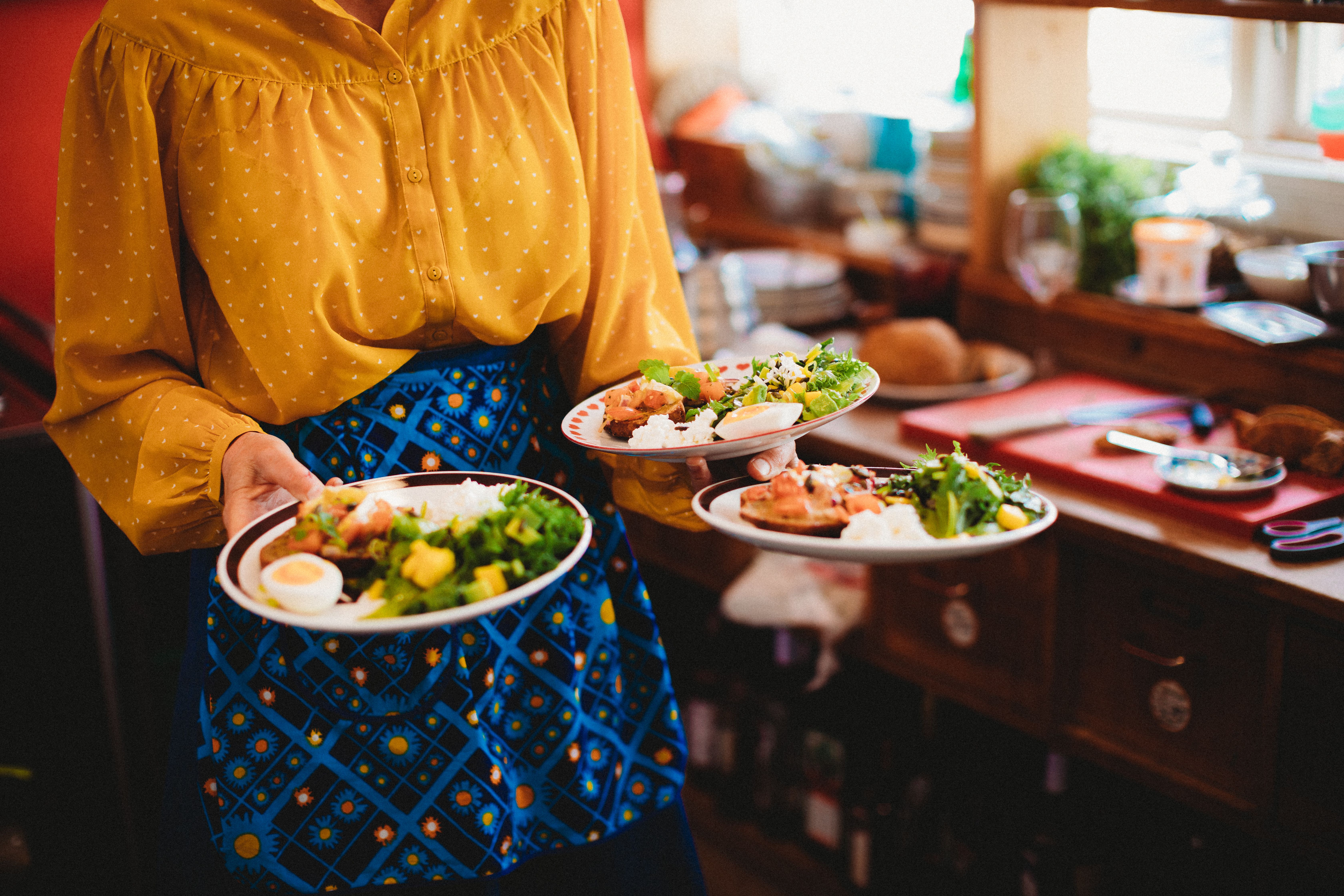 A woman carrying three plates of food at Sødahlhuset in Åndalsnes in Northwest, Fjord Norway.