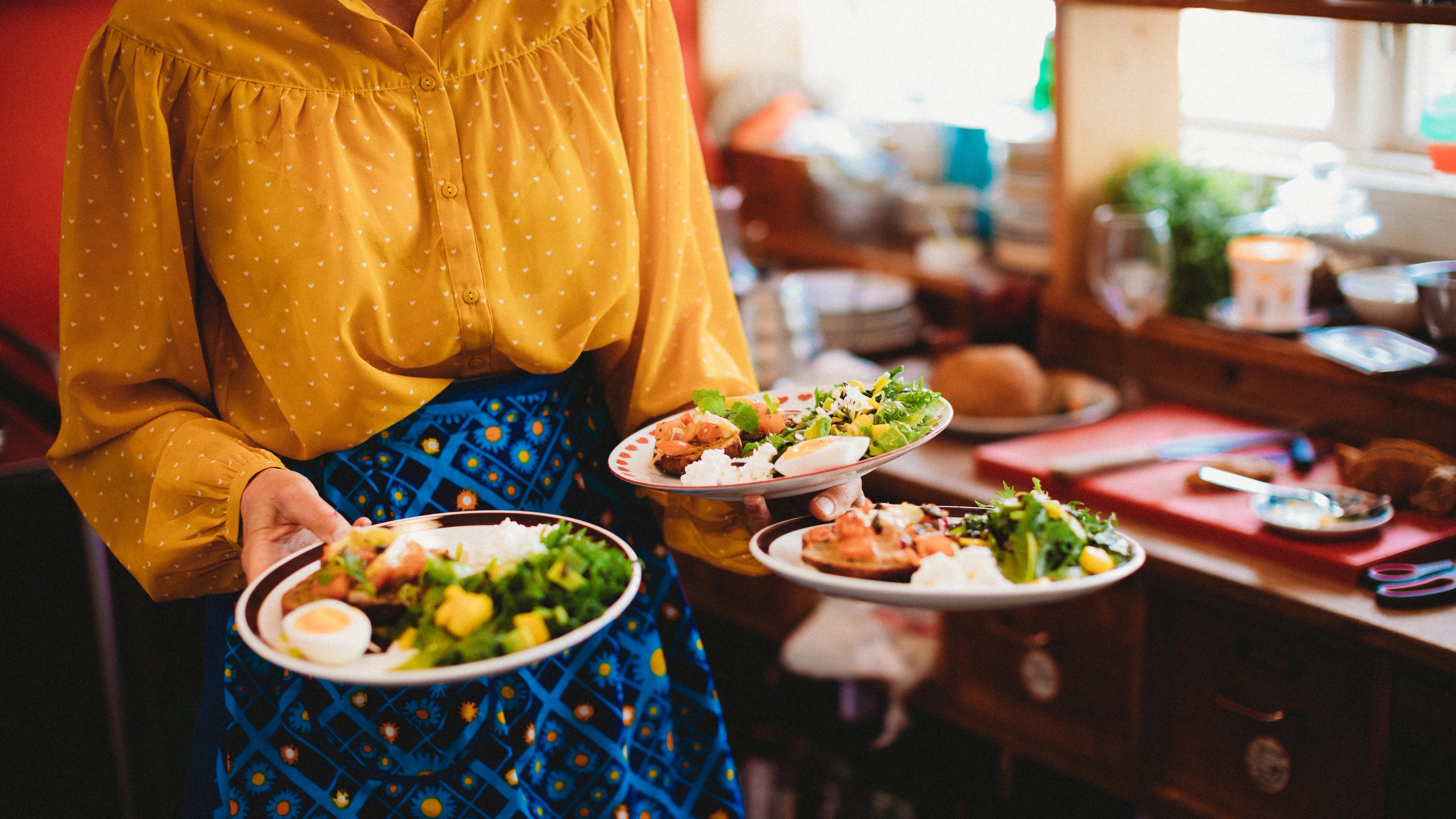 A woman carrying three plates of food at Sødahlhuset in Åndalsnes in Northwest, Fjord Norway.