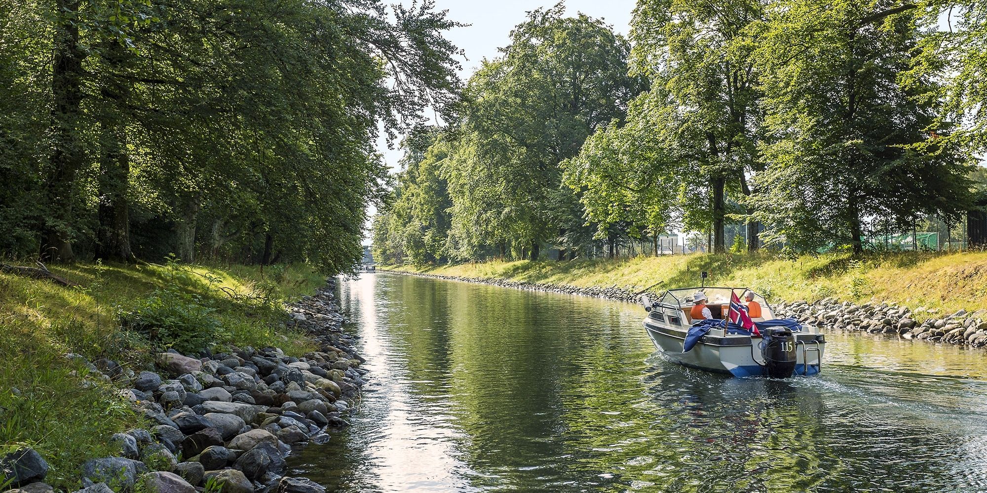 En båt kjører i rolig fart gjennom Hortenskanalen en sommerdag