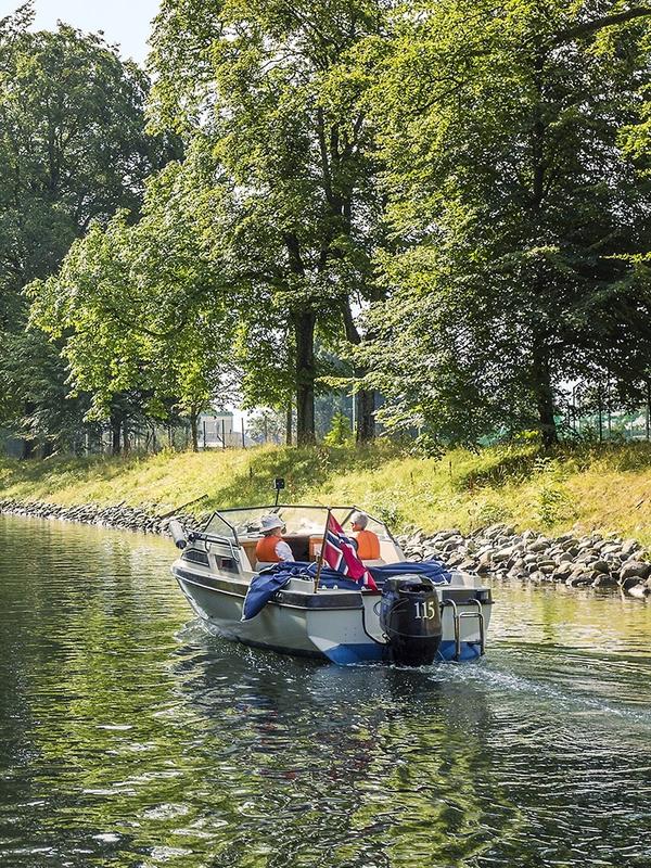 En båt kjører i rolig fart gjennom Hortenskanalen en sommerdag