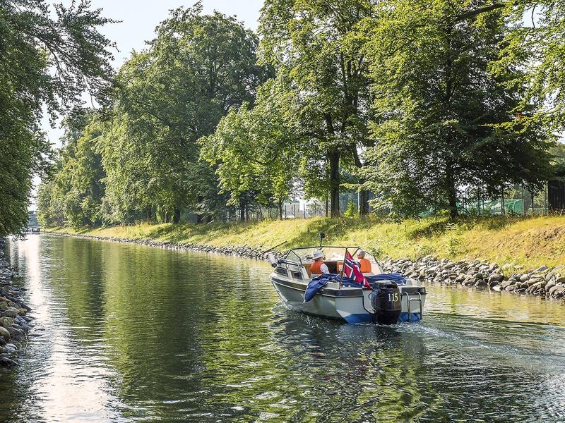 En båt kjører i rolig fart gjennom Hortenskanalen en sommerdag