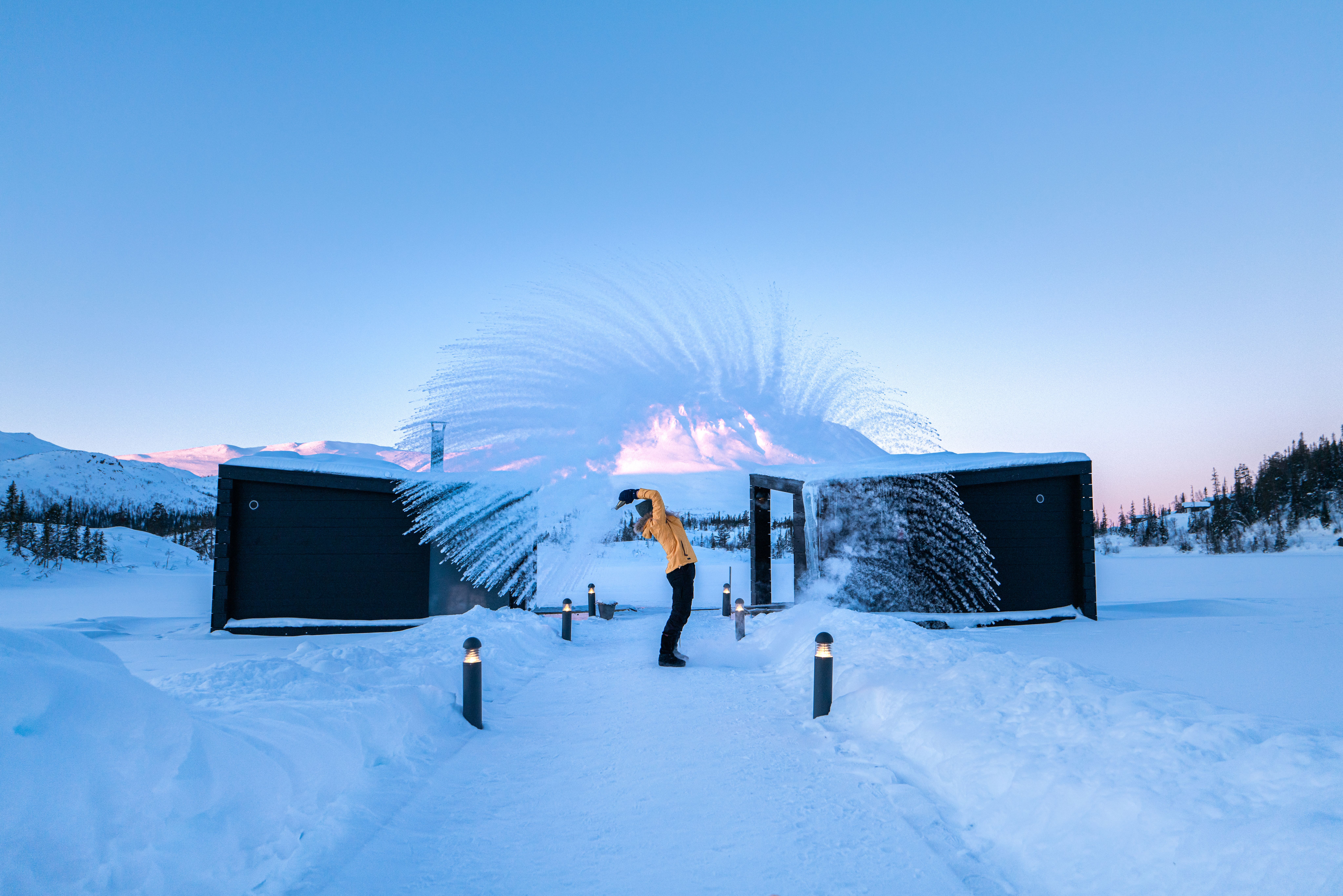 Girl throwing snow in front of the floating saunas at Gausta in winter, Telemark
