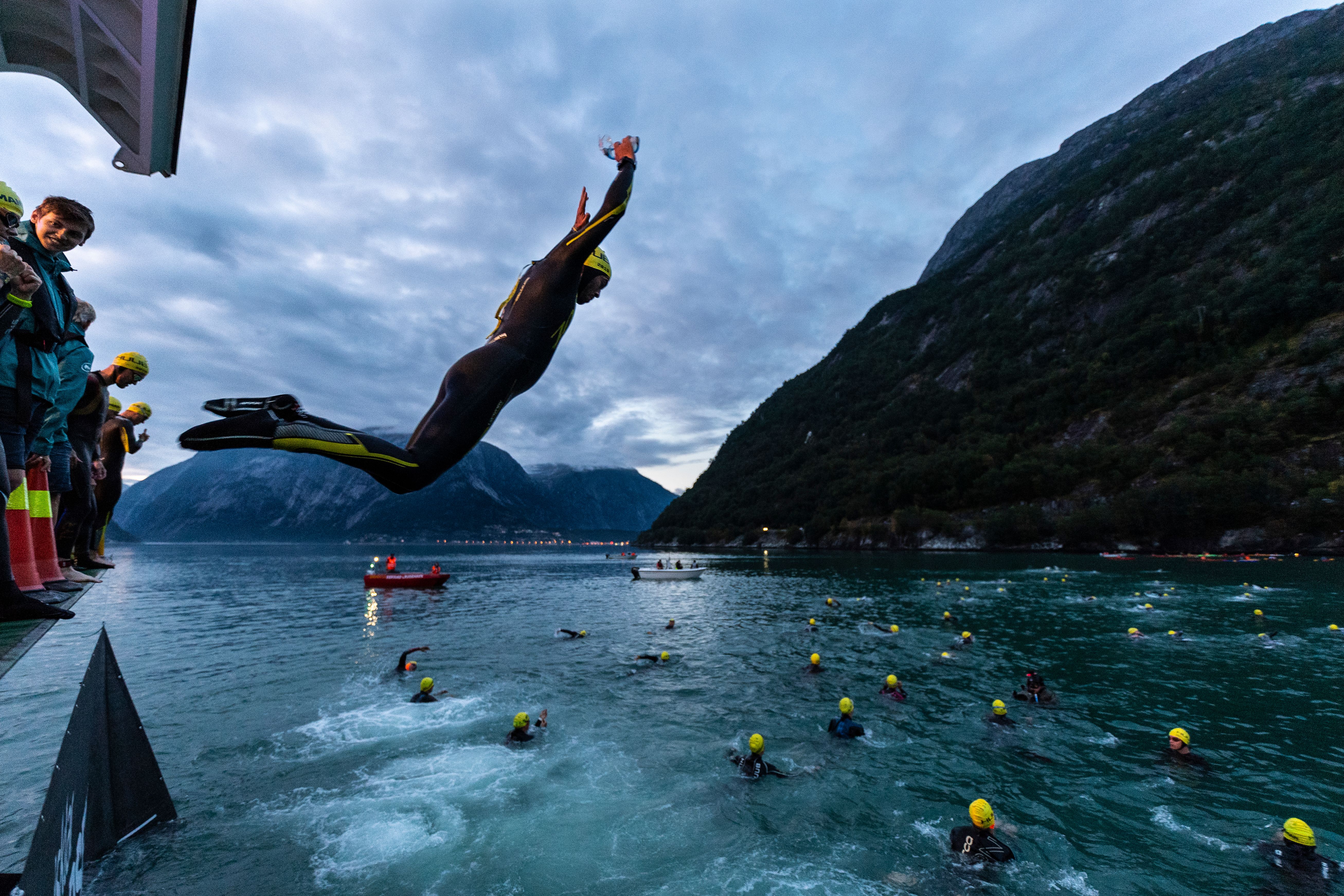A person in wetsuit jumping into the fjord in Northern Norway as part of the Norseman competition