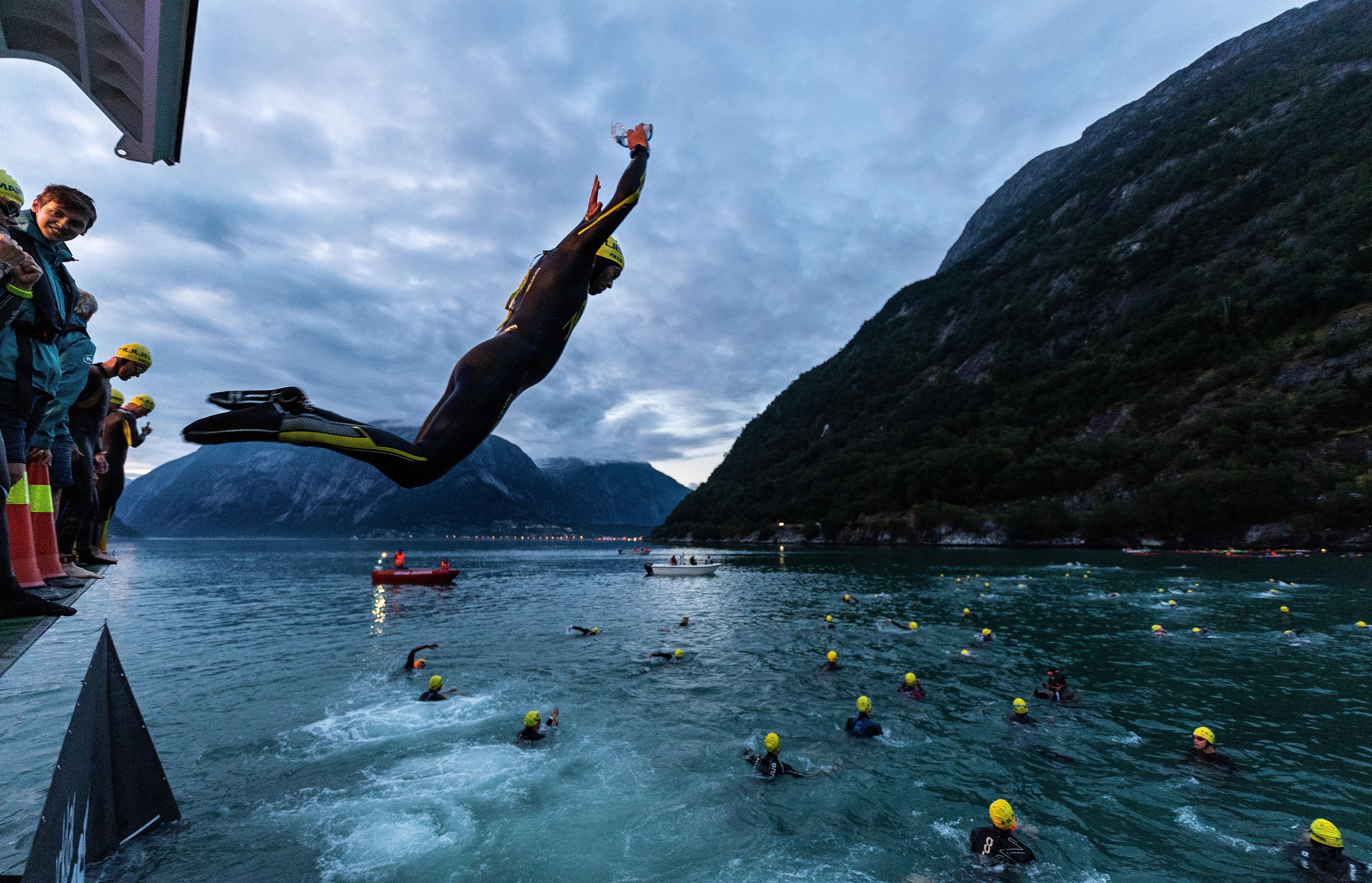 A person in wetsuit jumping into the fjord in Northern Norway as part of the Norseman competition