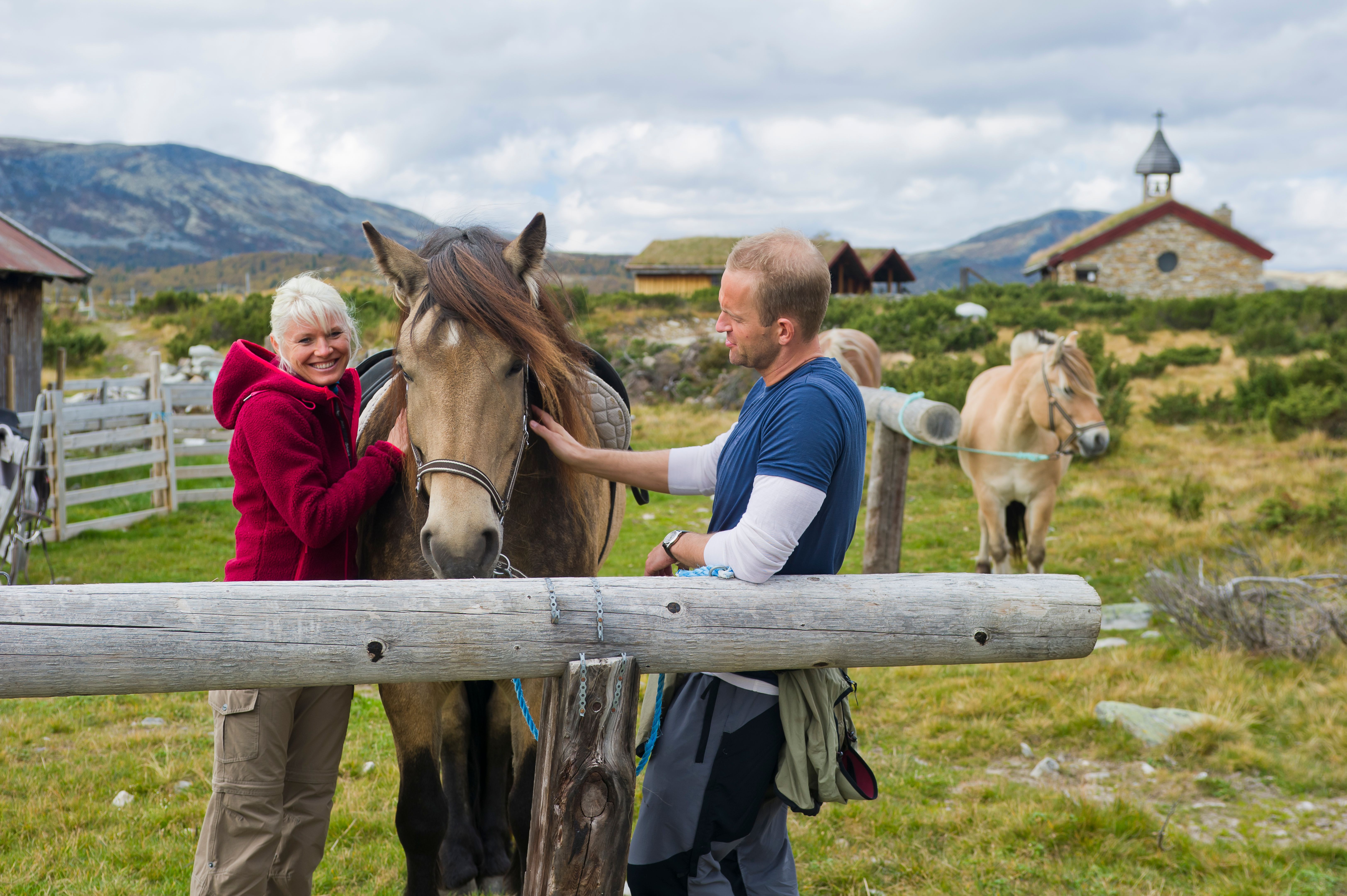 A woman and a man with a horse outside of Venabu summer pasture farm, Gudbrandsdalen.