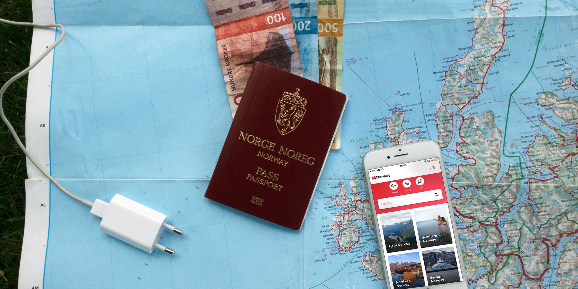 Plan your trip to Norway: A map, bank notes, a mobile phone charger, and a mobile phone with the Visit Norway app