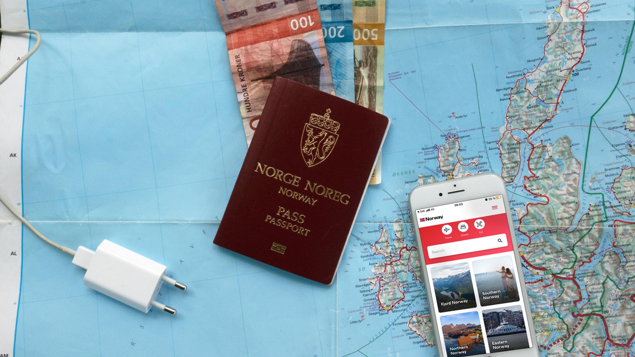 Plan your trip to Norway: A map, bank notes, a mobile phone charger, and a mobile phone with the Visit Norway app