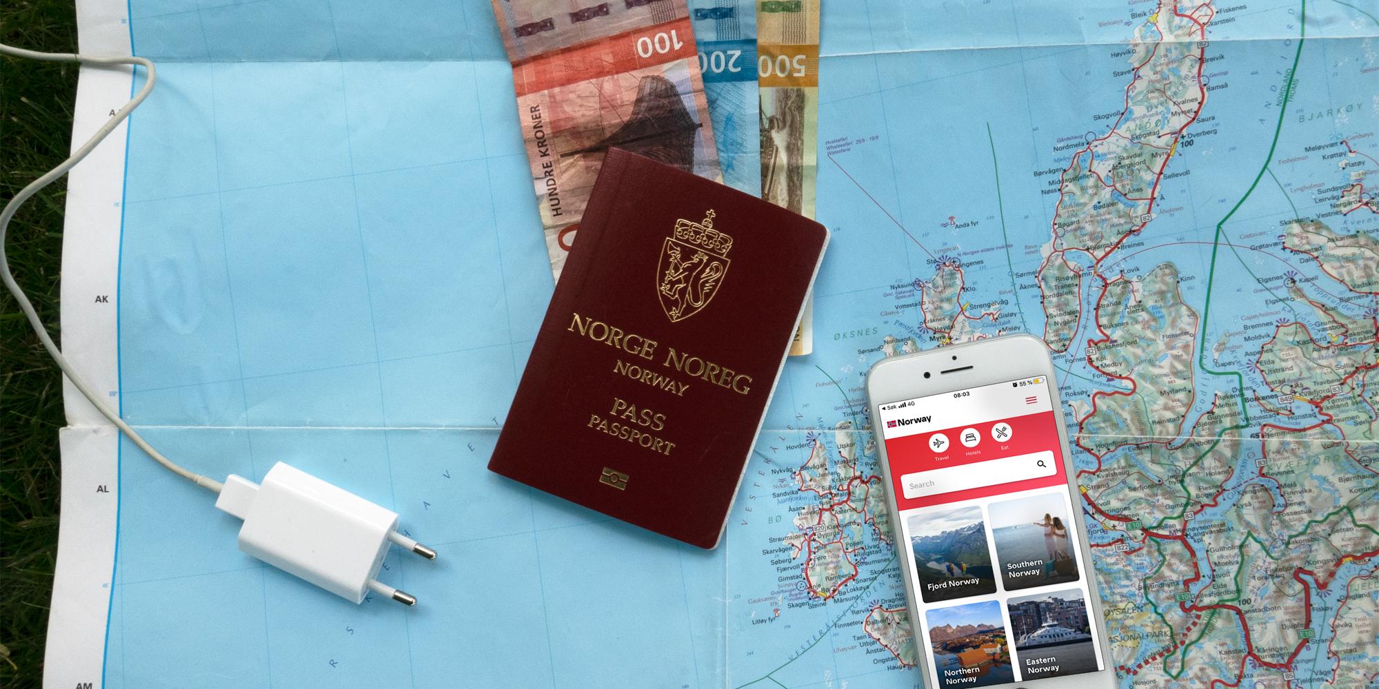 Plan your trip to Norway: A map, bank notes, a mobile phone charger, and a mobile phone with the Visit Norway app