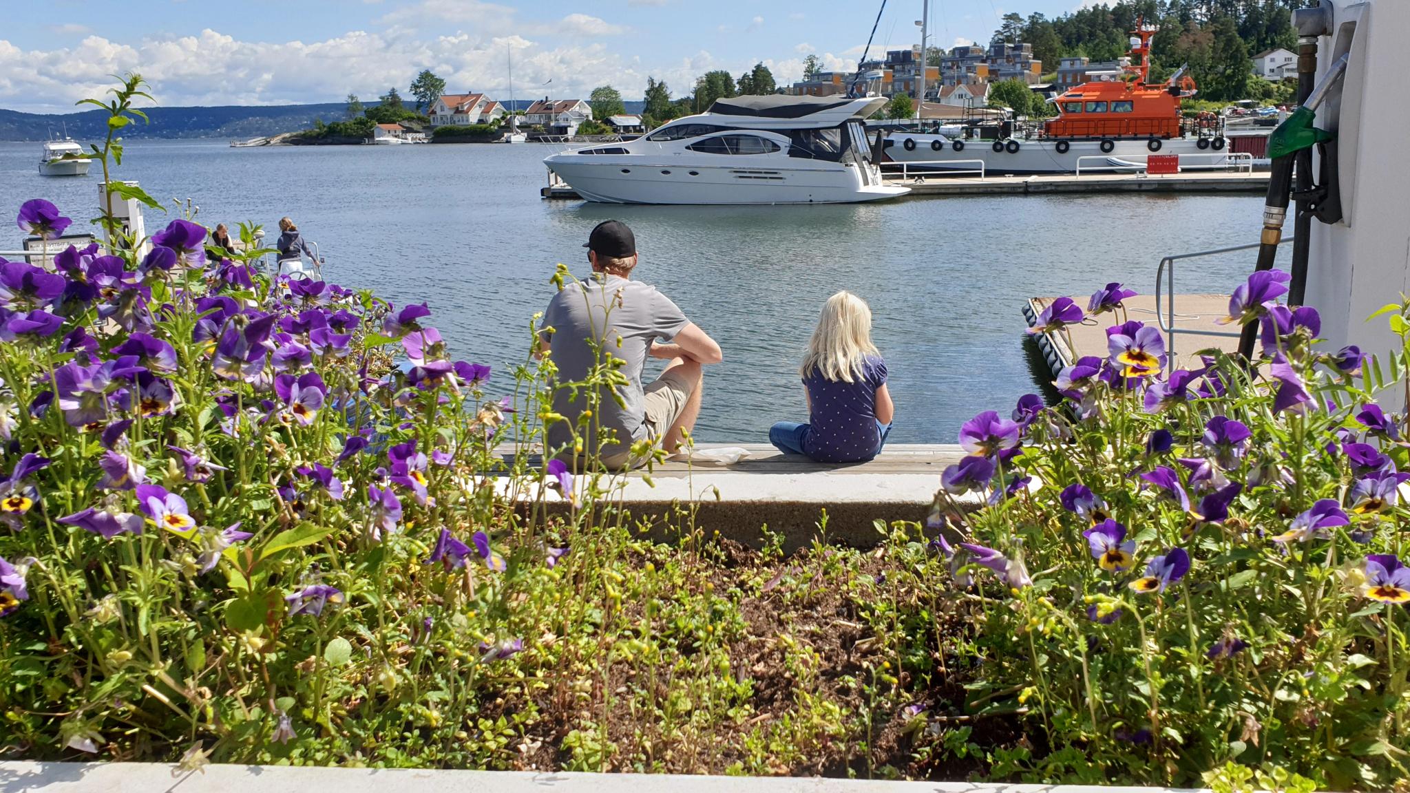 Father and daughter sitting by the marina in Vollen in Asker in the Oslo Region, Eastern Norway